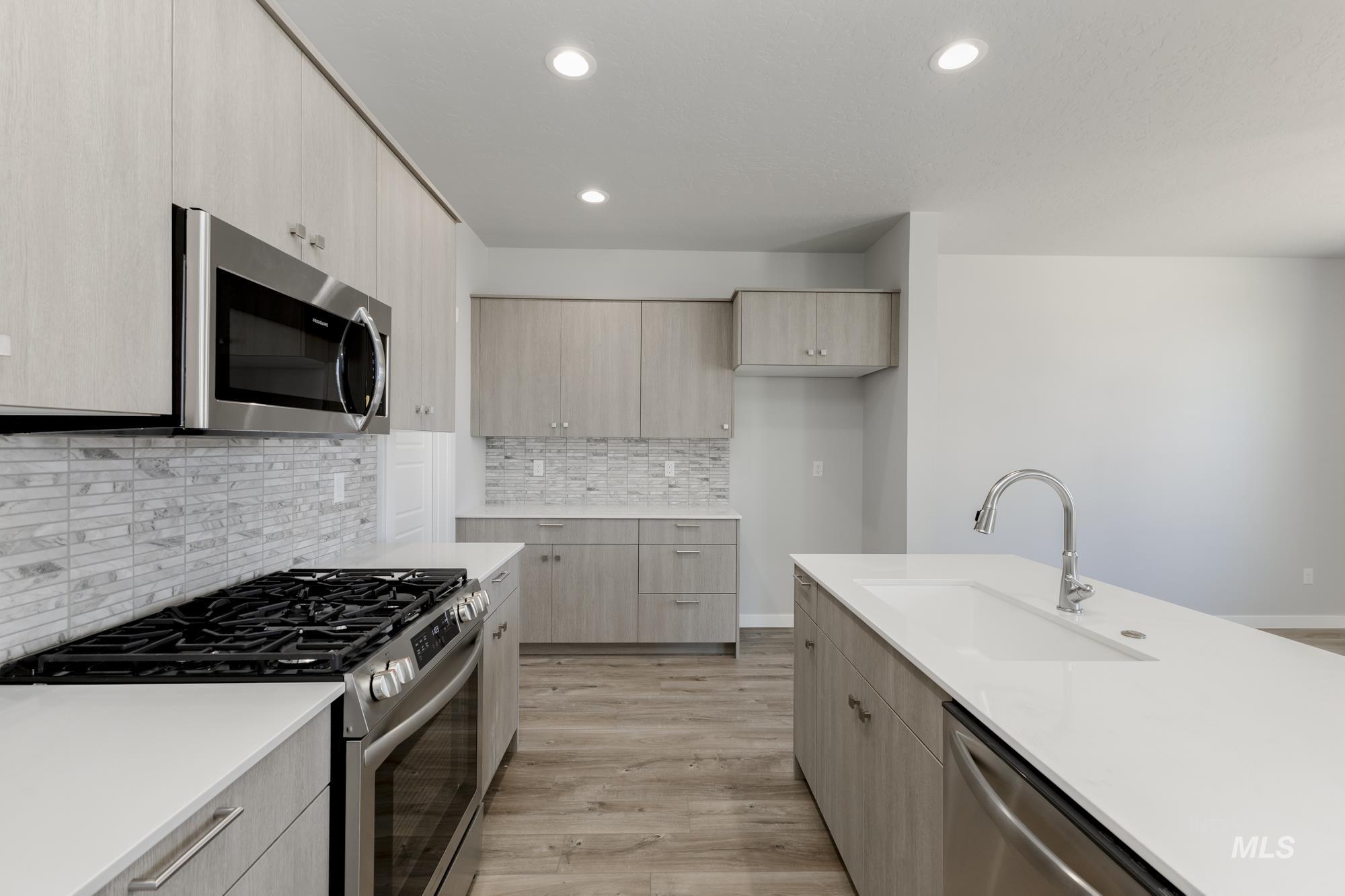 Kitchen with stainless steel appliances, light countertops, recessed lighting, modern cabinets, and light wood-style floors