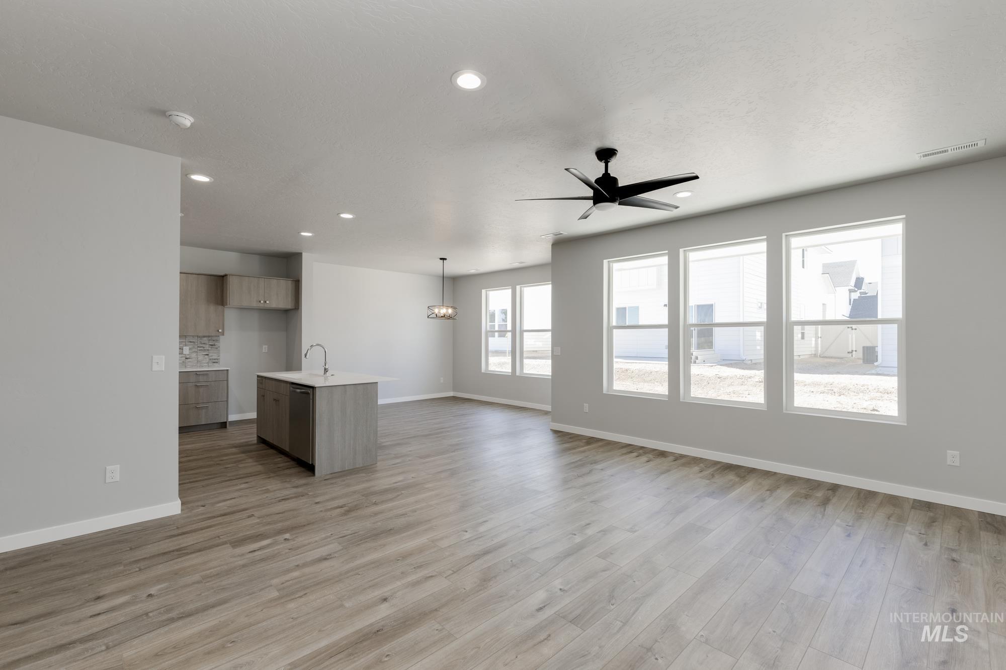 Unfurnished living room featuring a ceiling fan, light wood-type flooring, and recessed lighting