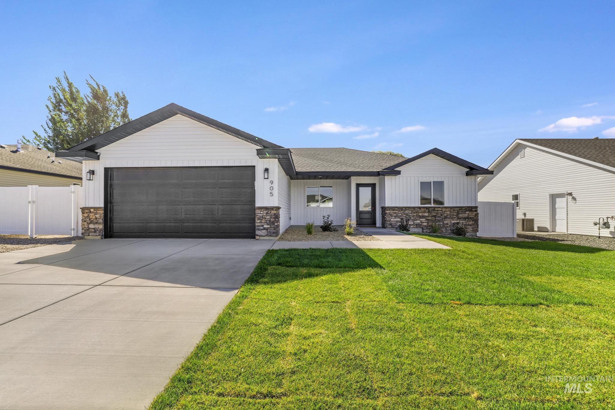 View of front facade with stone siding, concrete driveway, a garage, and board and batten siding