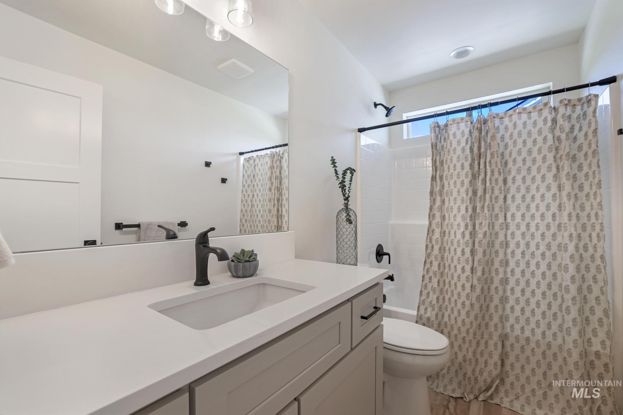 Bathroom featuring shower / tub combo with curtain, vanity, and light wood finished floors