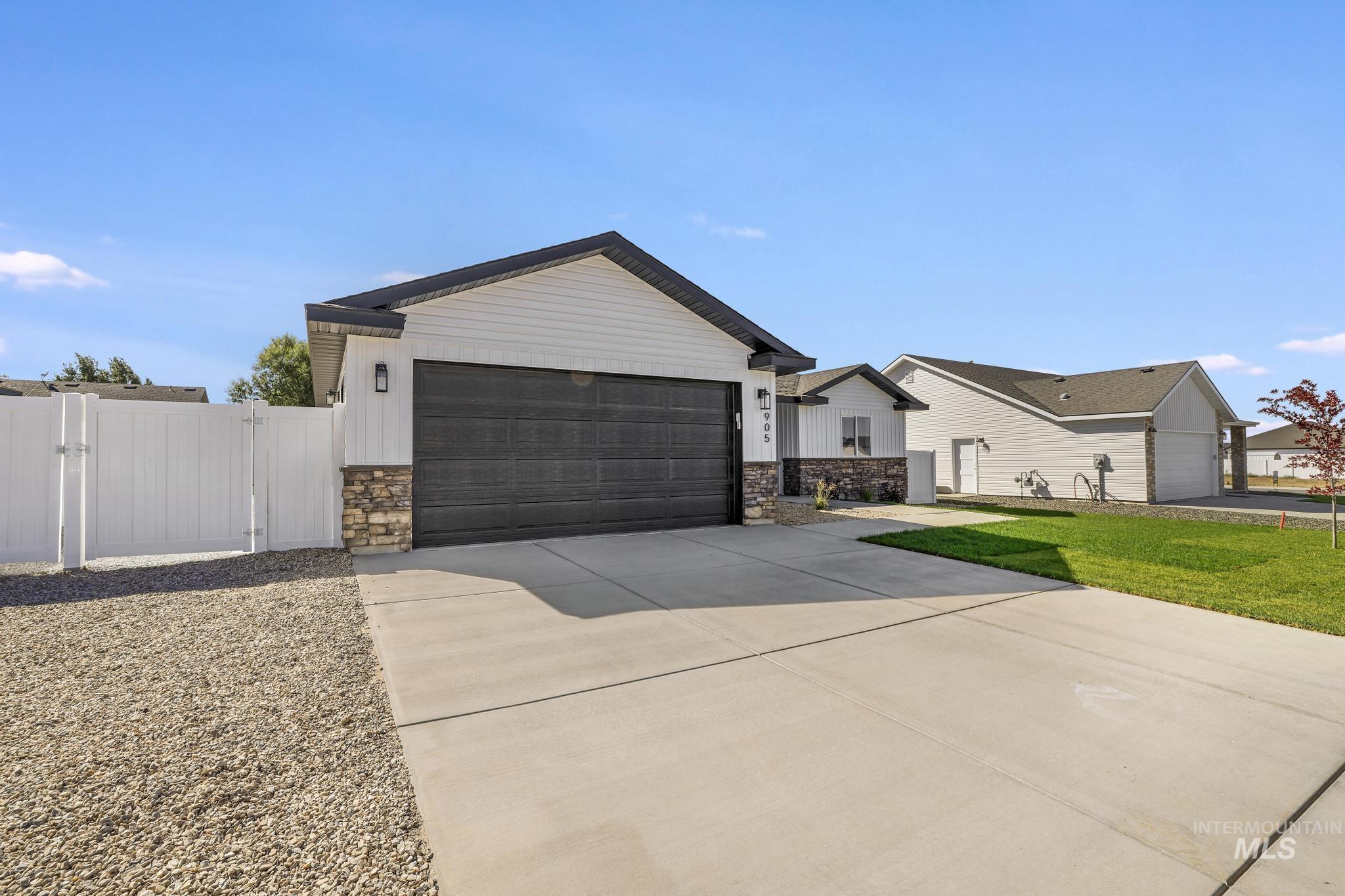 View of front of house featuring stone siding, a gate, a garage, and concrete driveway