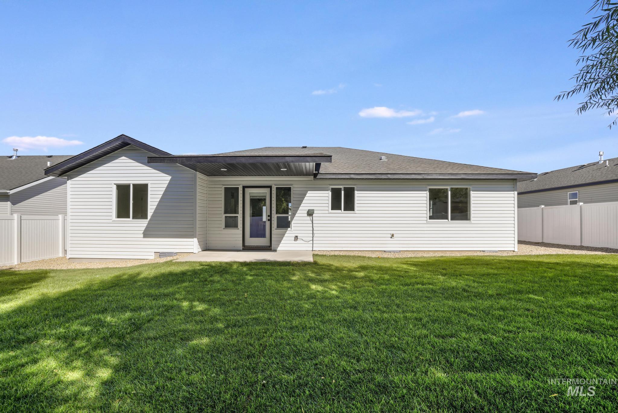 Rear view of house with a patio area and a shingled roof