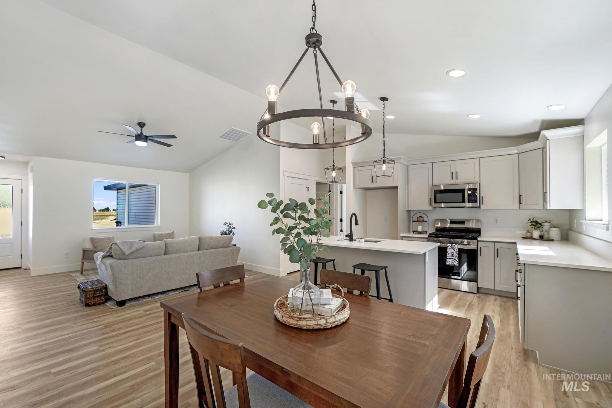 Dining area featuring light wood-type flooring, a ceiling fan, a chandelier, recessed lighting, and high vaulted ceiling