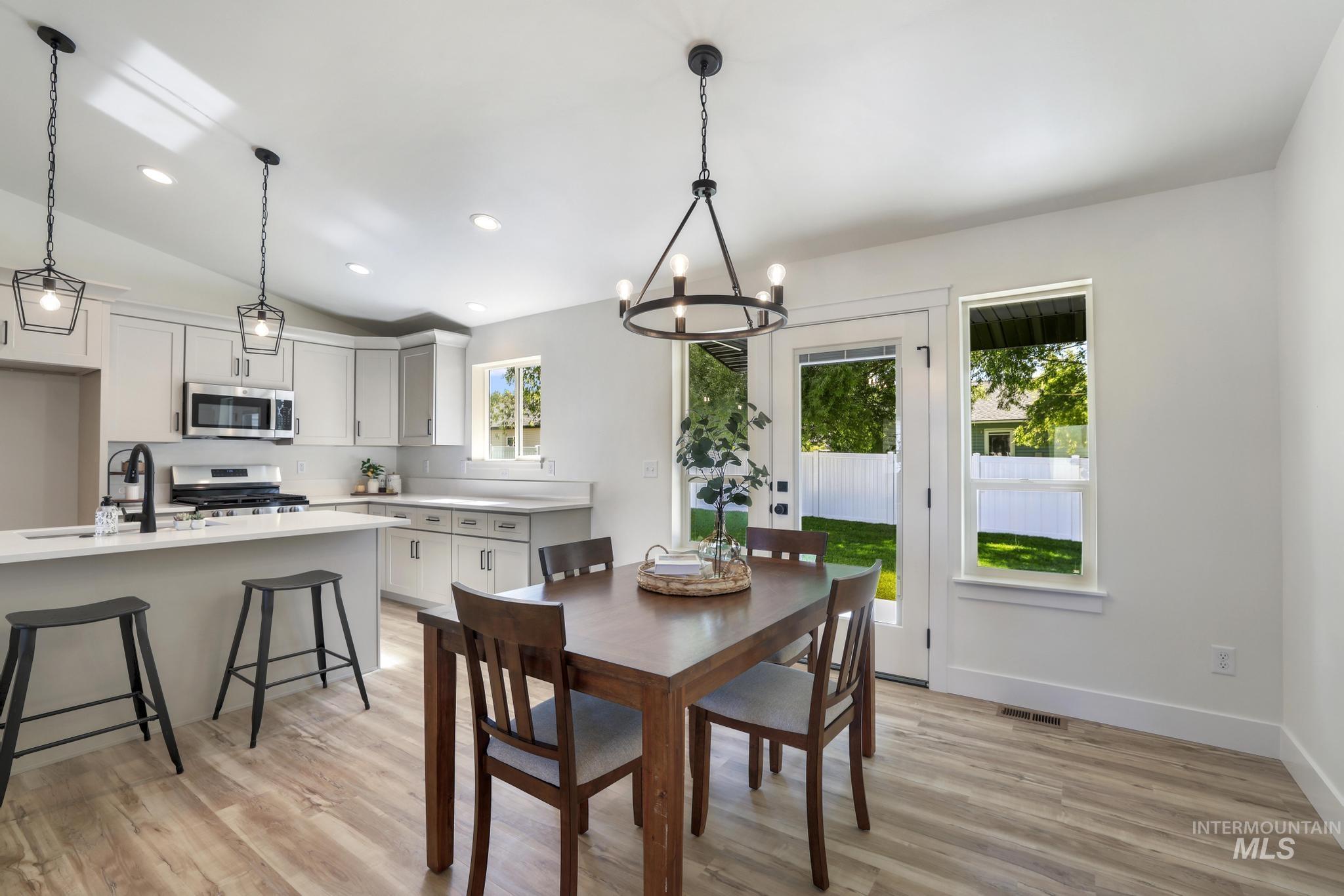 Dining room with light wood-style floors, a chandelier, recessed lighting, and vaulted ceiling