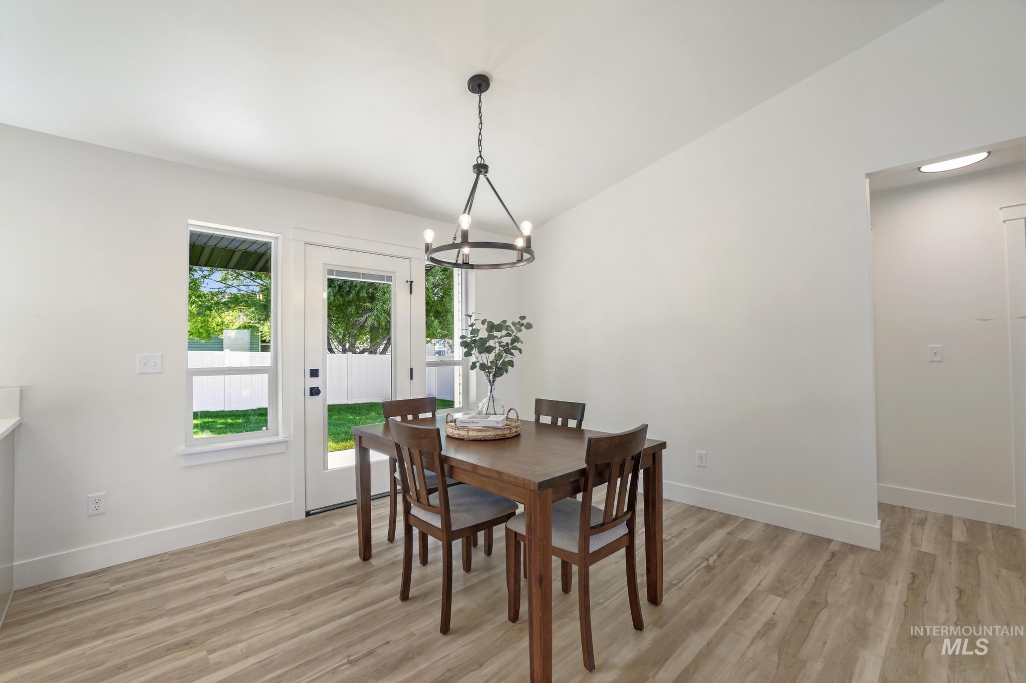 Dining space featuring light wood-style flooring, lofted ceiling, and a chandelier