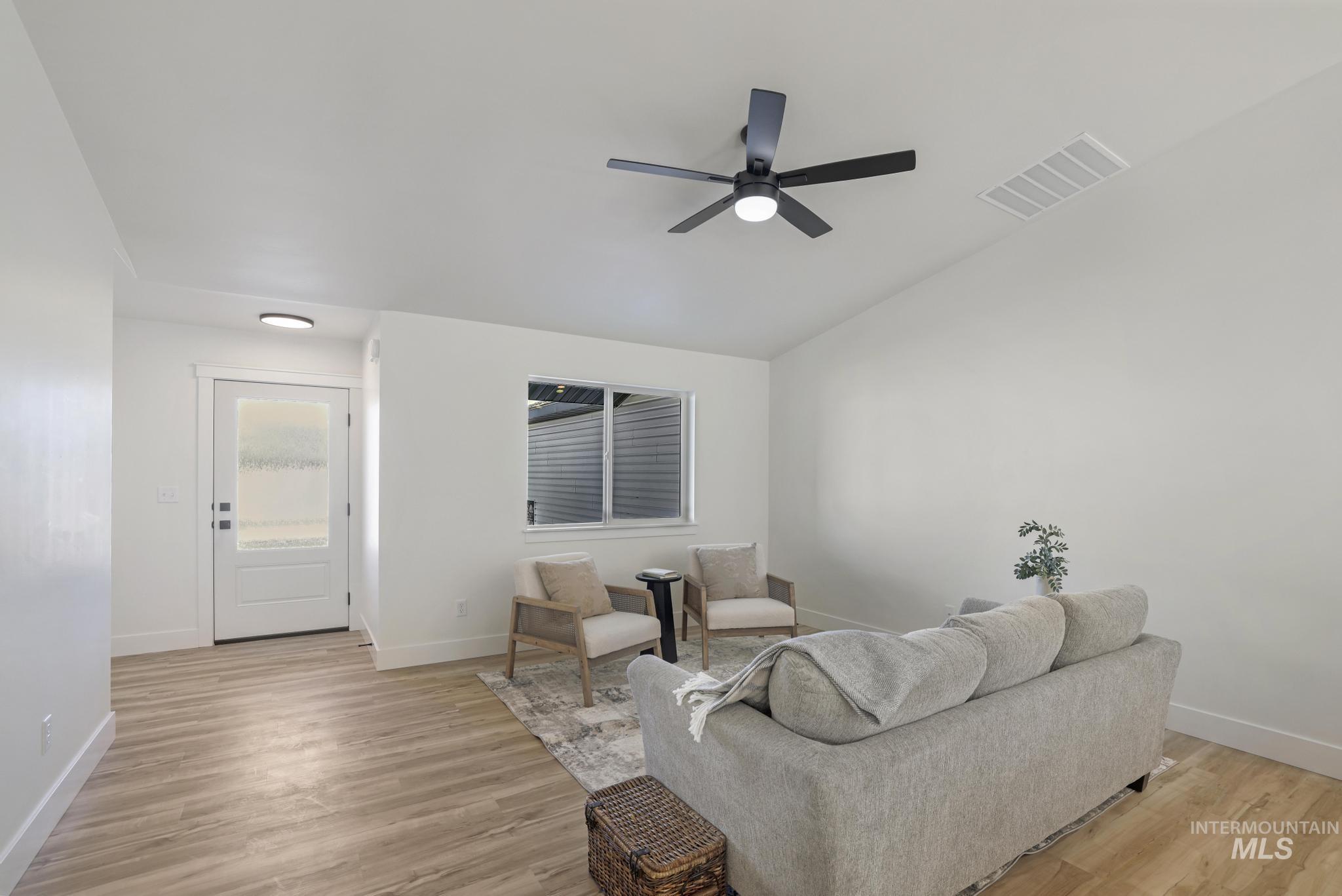 Living area featuring light wood-style floors, vaulted ceiling, and ceiling fan