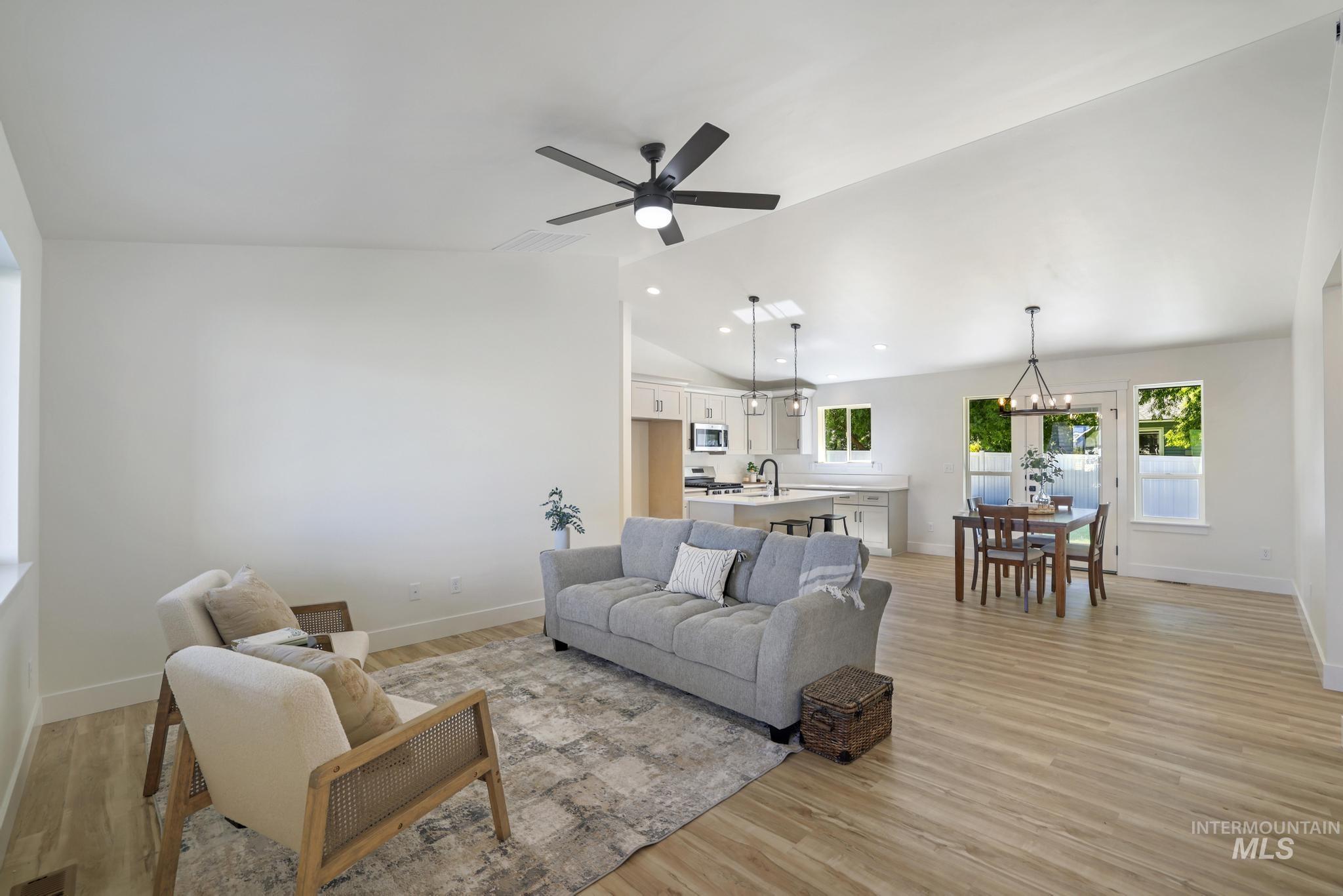 Living area with light wood-style flooring, ceiling fan, recessed lighting, a chandelier, and high vaulted ceiling