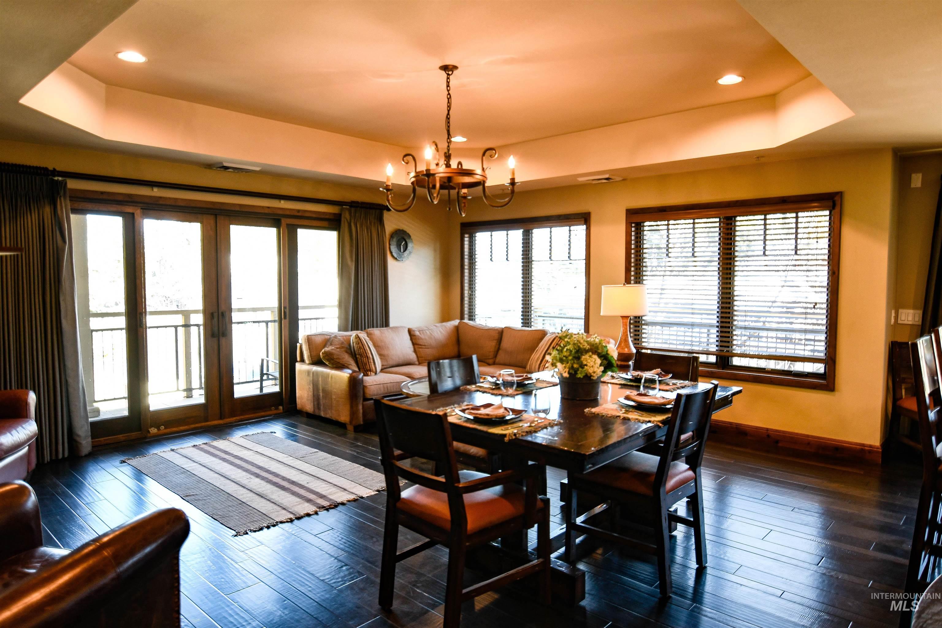 Dining room with a tray ceiling, french doors, recessed lighting, dark wood-style flooring, and a chandelier