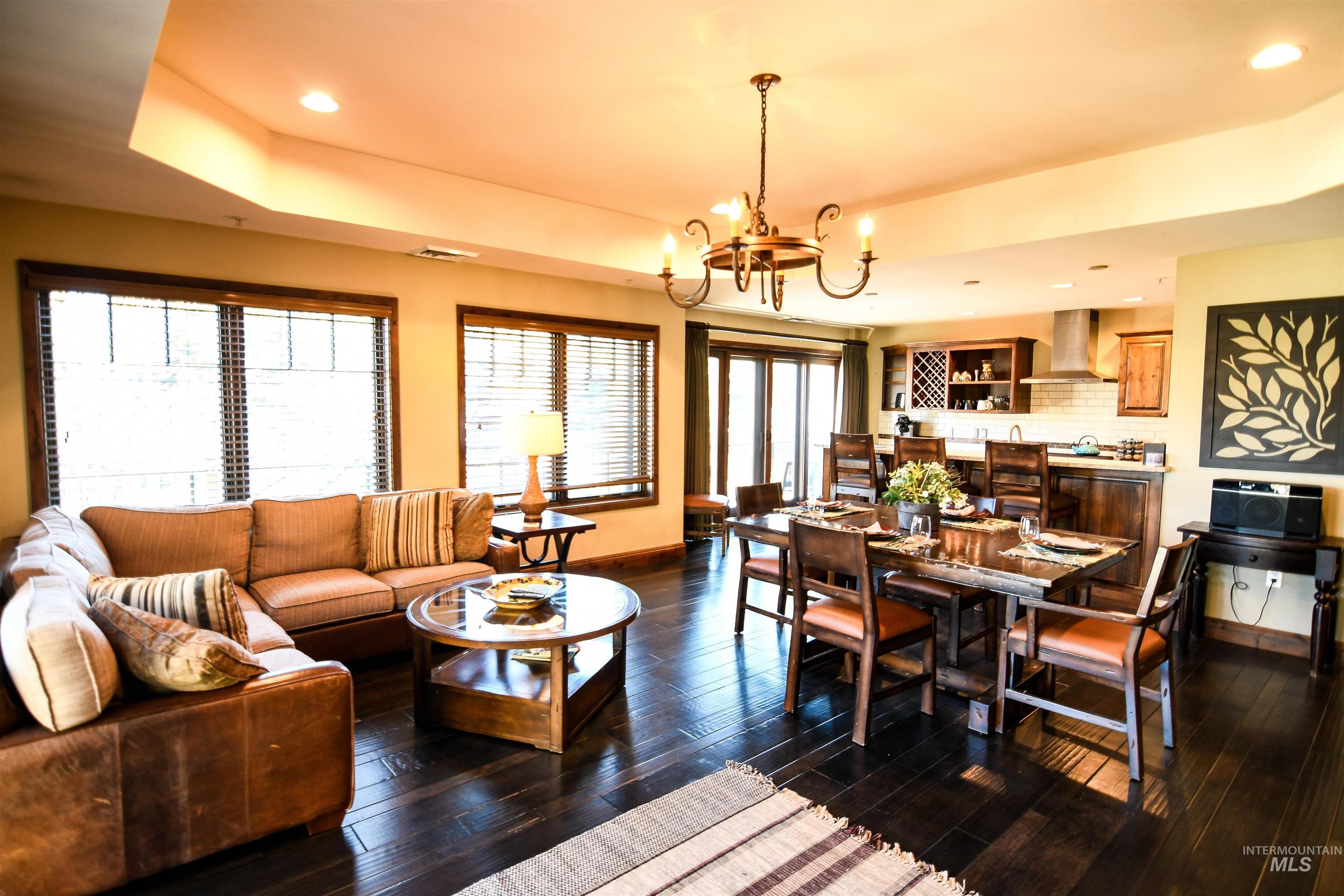 Living area featuring recessed lighting, dark wood finished floors, a chandelier, and a tray ceiling