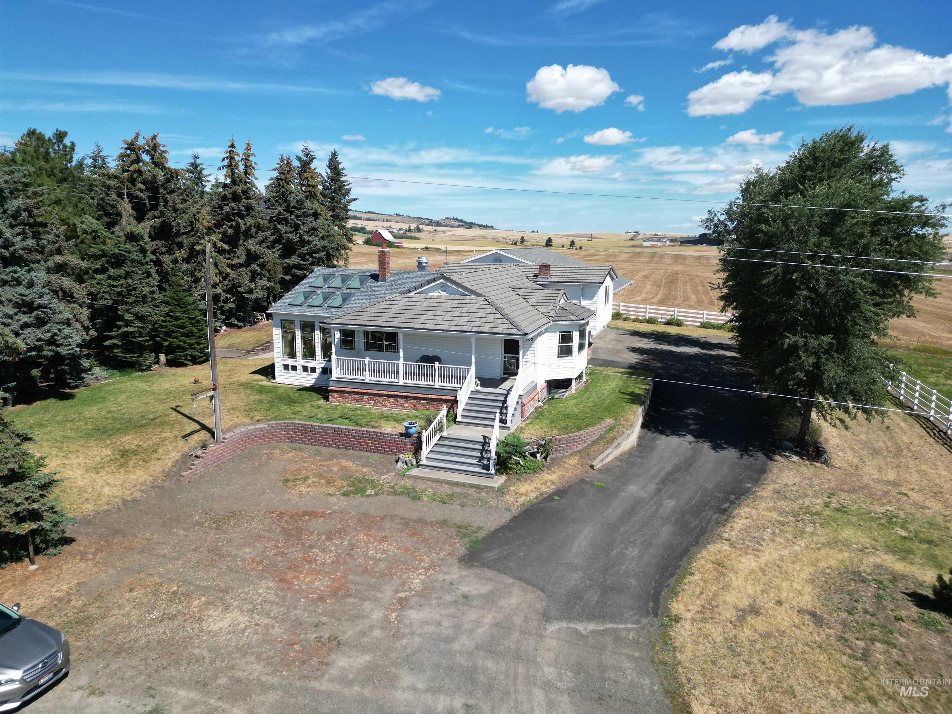 View of front of house featuring driveway, covered porch, a tiled roof, and stairway