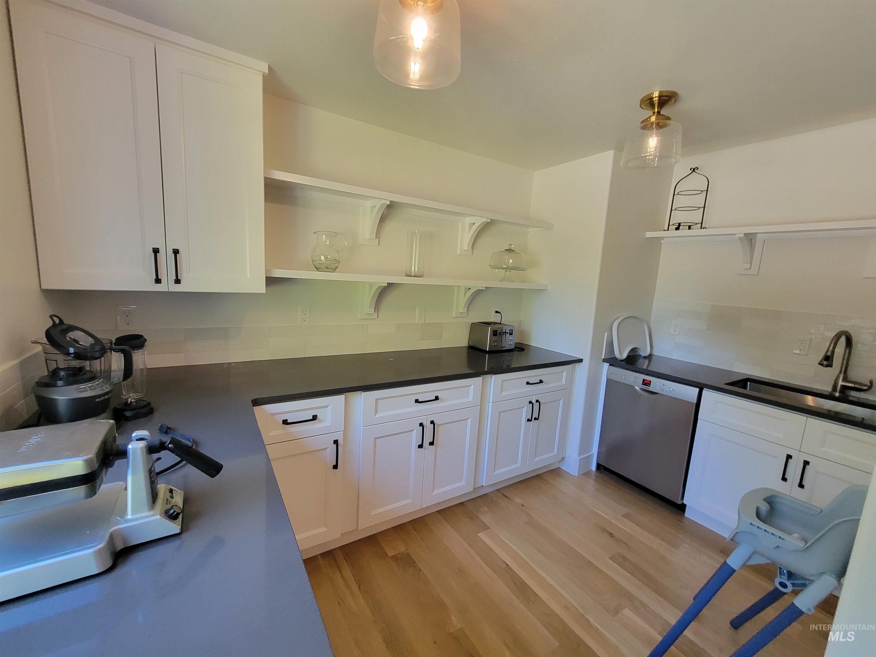 Kitchen with open shelves, white cabinetry, dishwasher, and light wood-style floors
