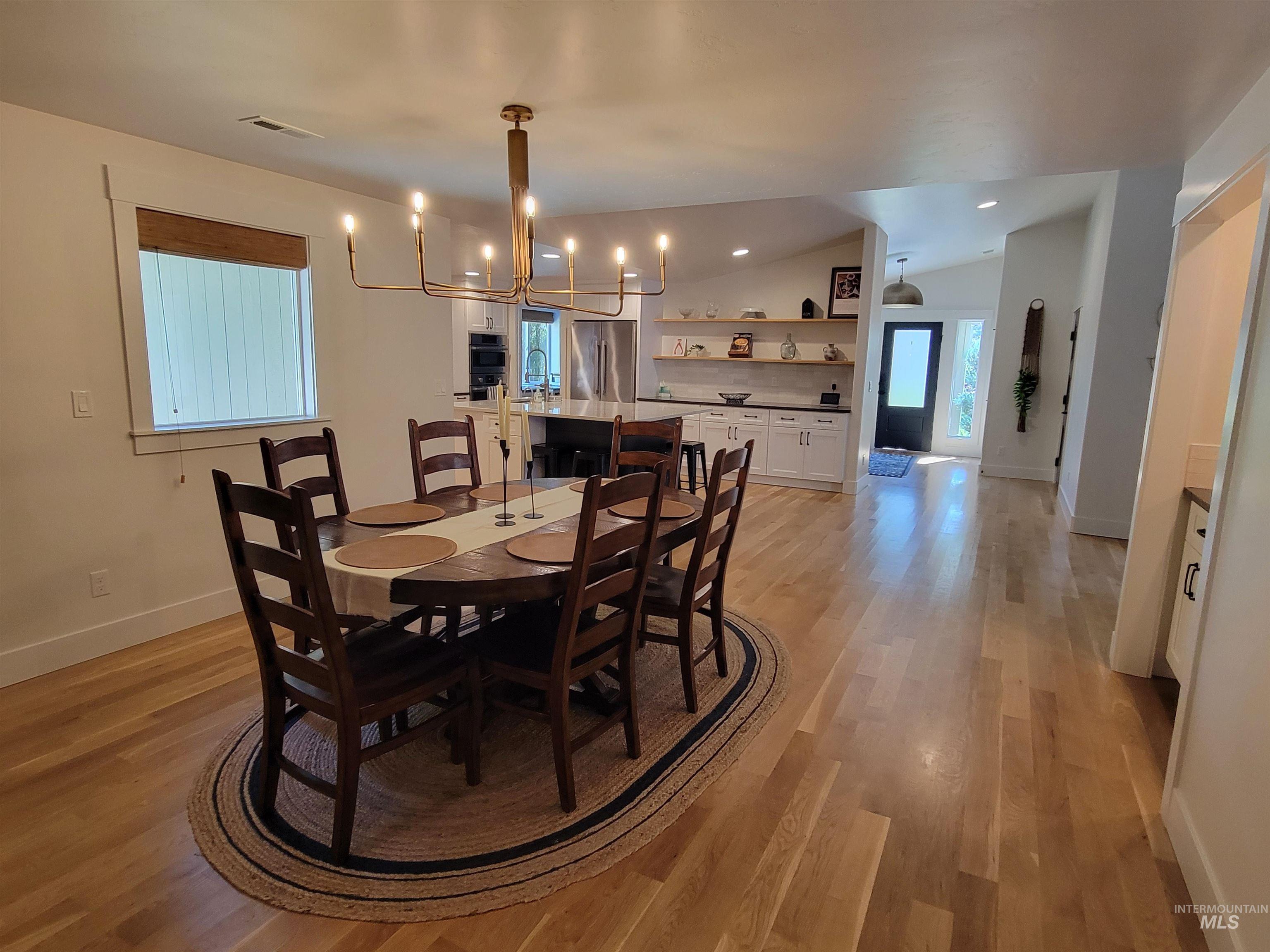 Dining room featuring a chandelier, lofted ceiling, light wood-style floors, and recessed lighting