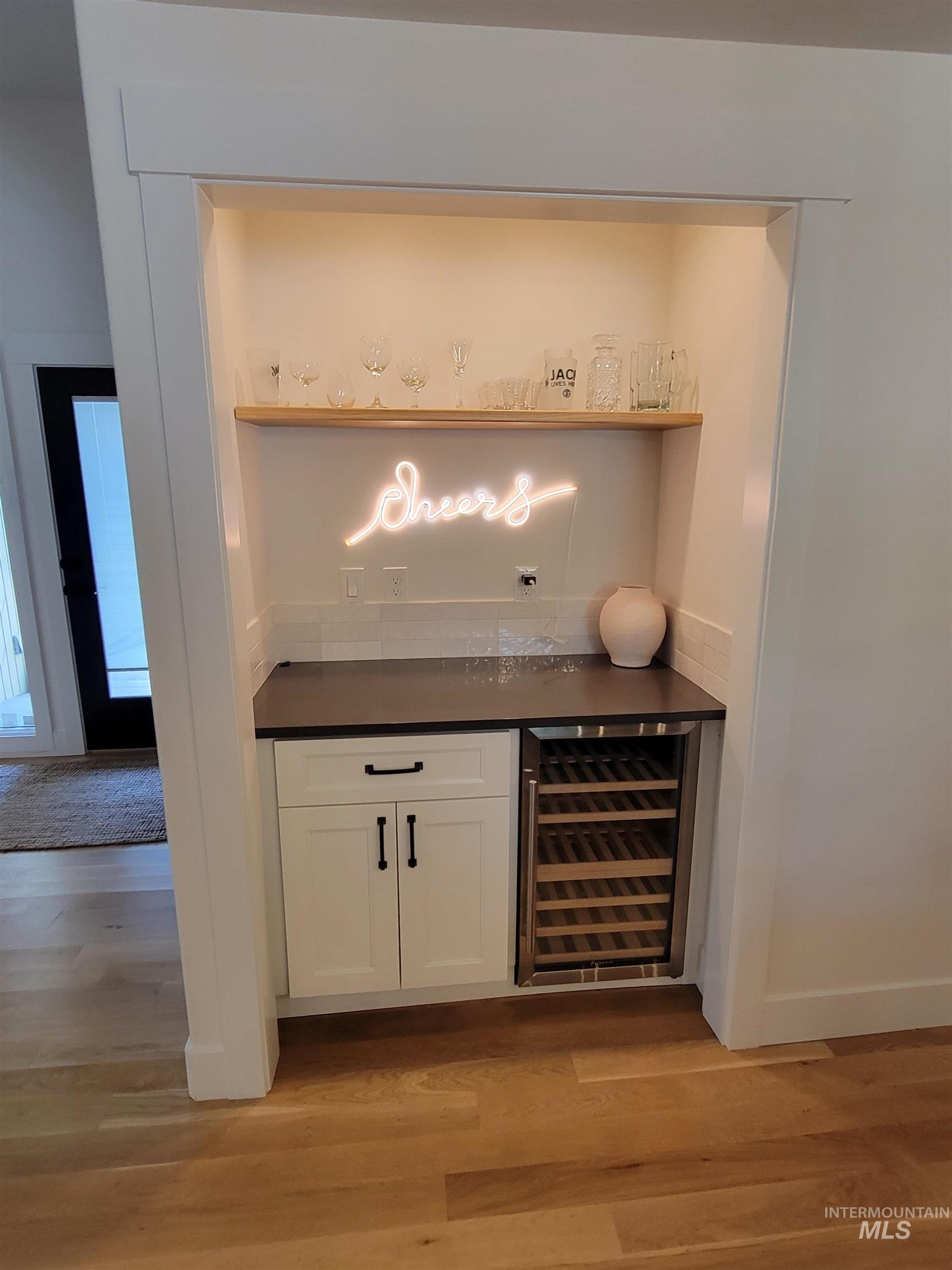 Indoor dry bar with light wood-style floors and beverage cooler