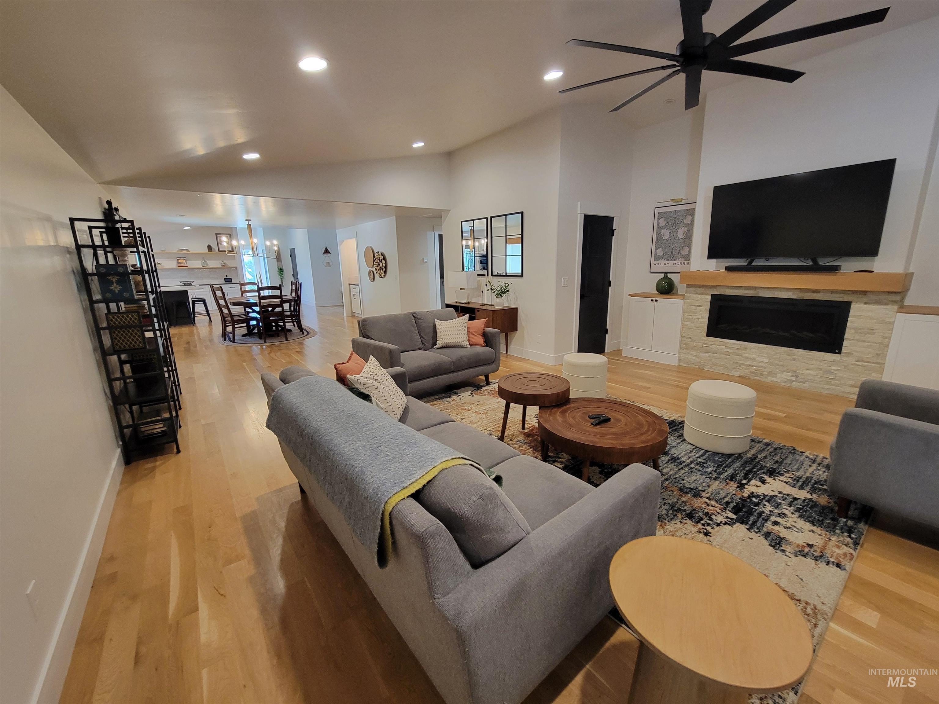Living area featuring wood finished floors, a fireplace, a ceiling fan, recessed lighting, and high vaulted ceiling
