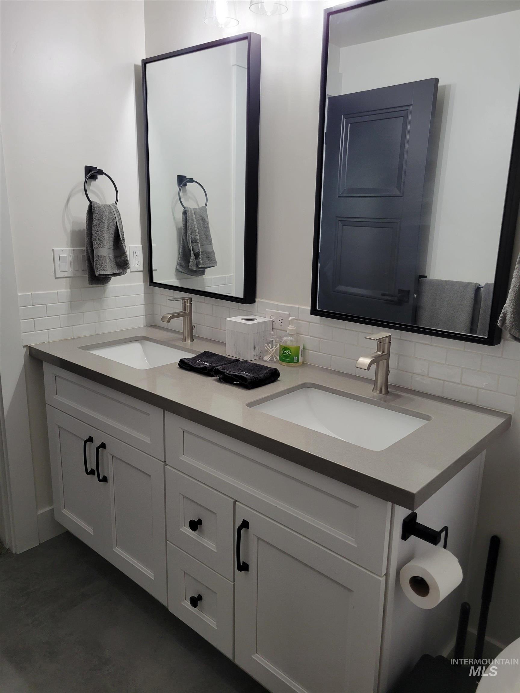 Full bathroom featuring double vanity and decorative backsplash