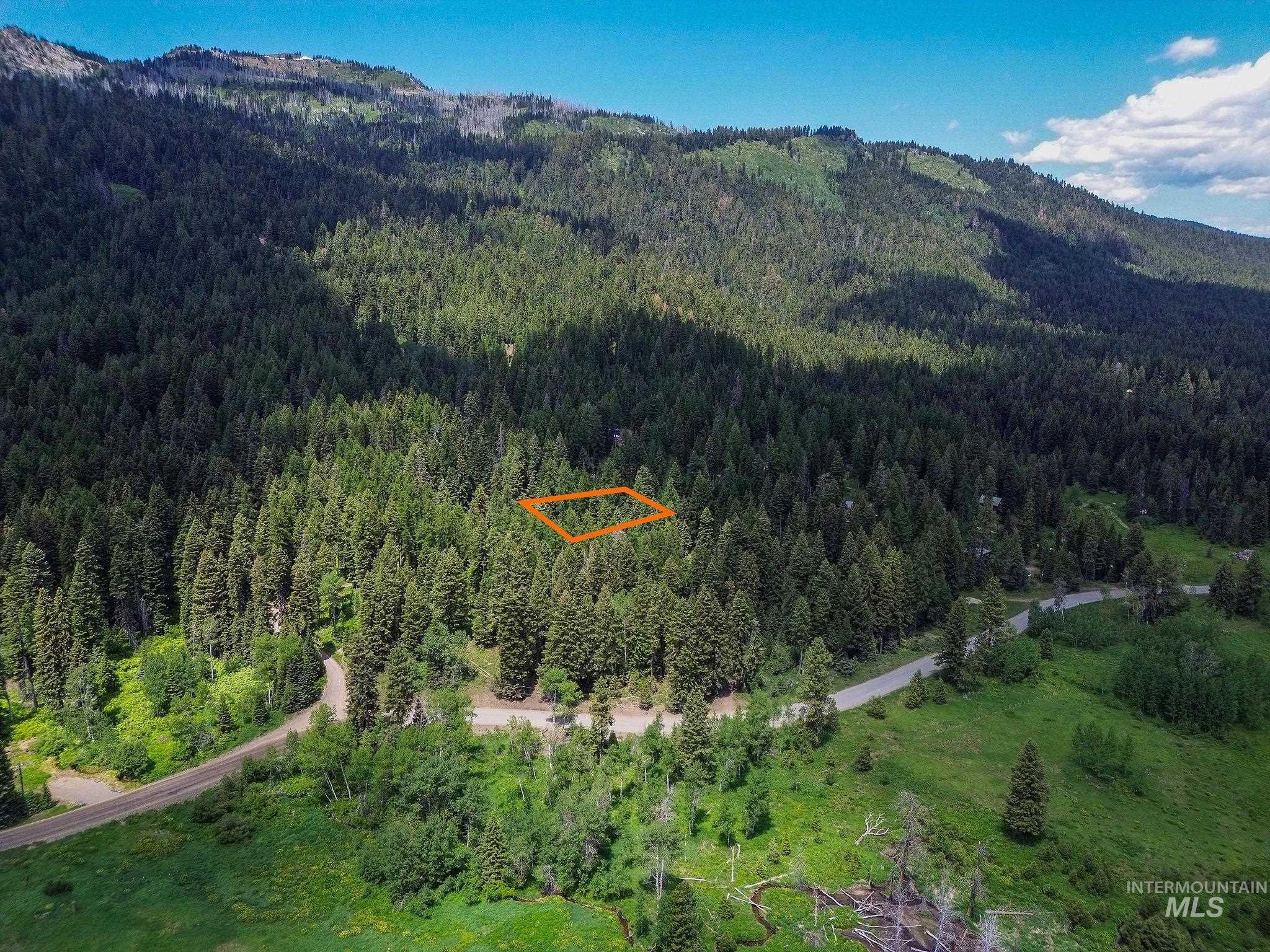 Aerial view of property and surrounding area with a mountain backdrop and property boundaries highlighted