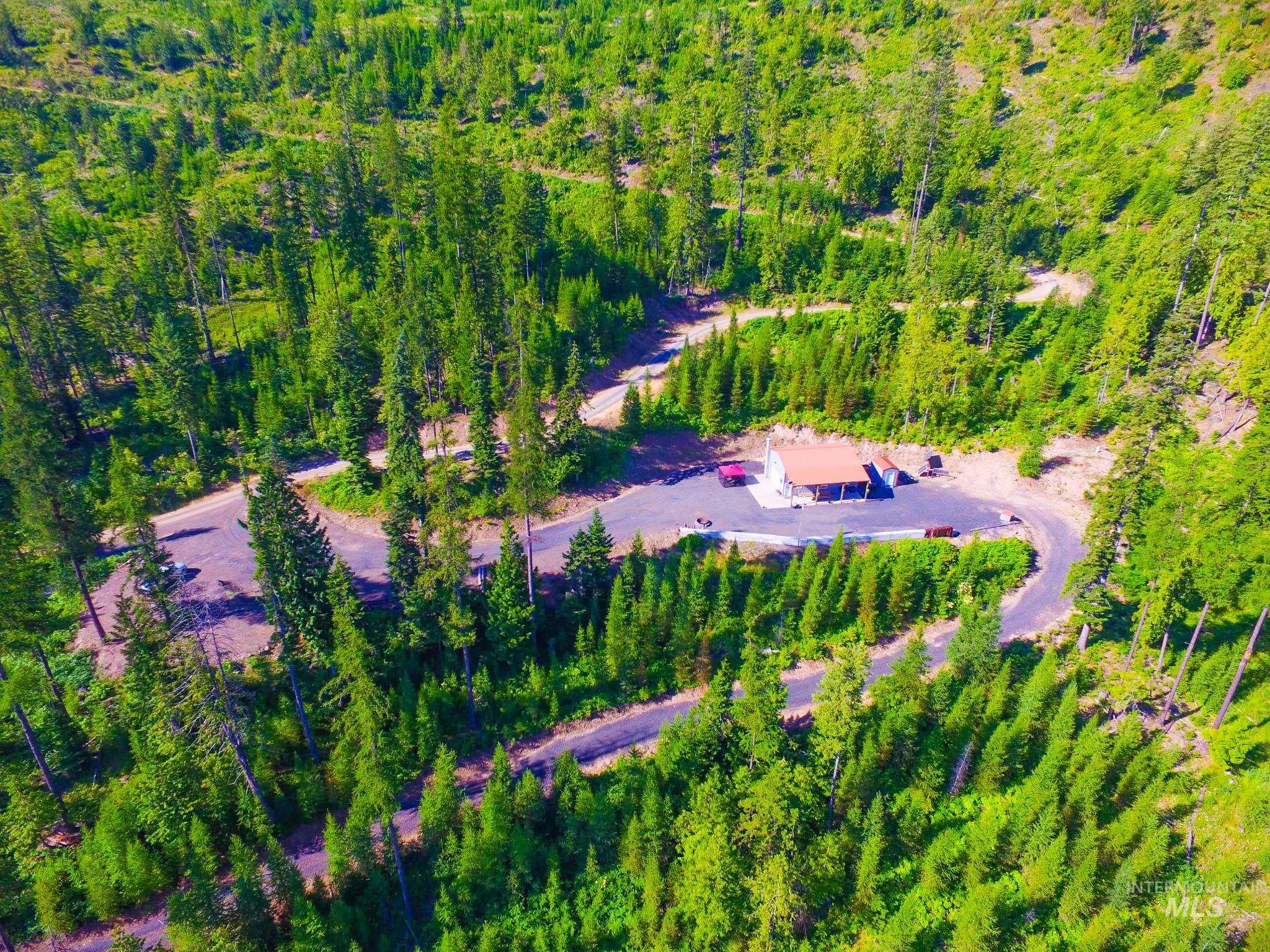 Aerial view of property and surrounding area featuring a forest