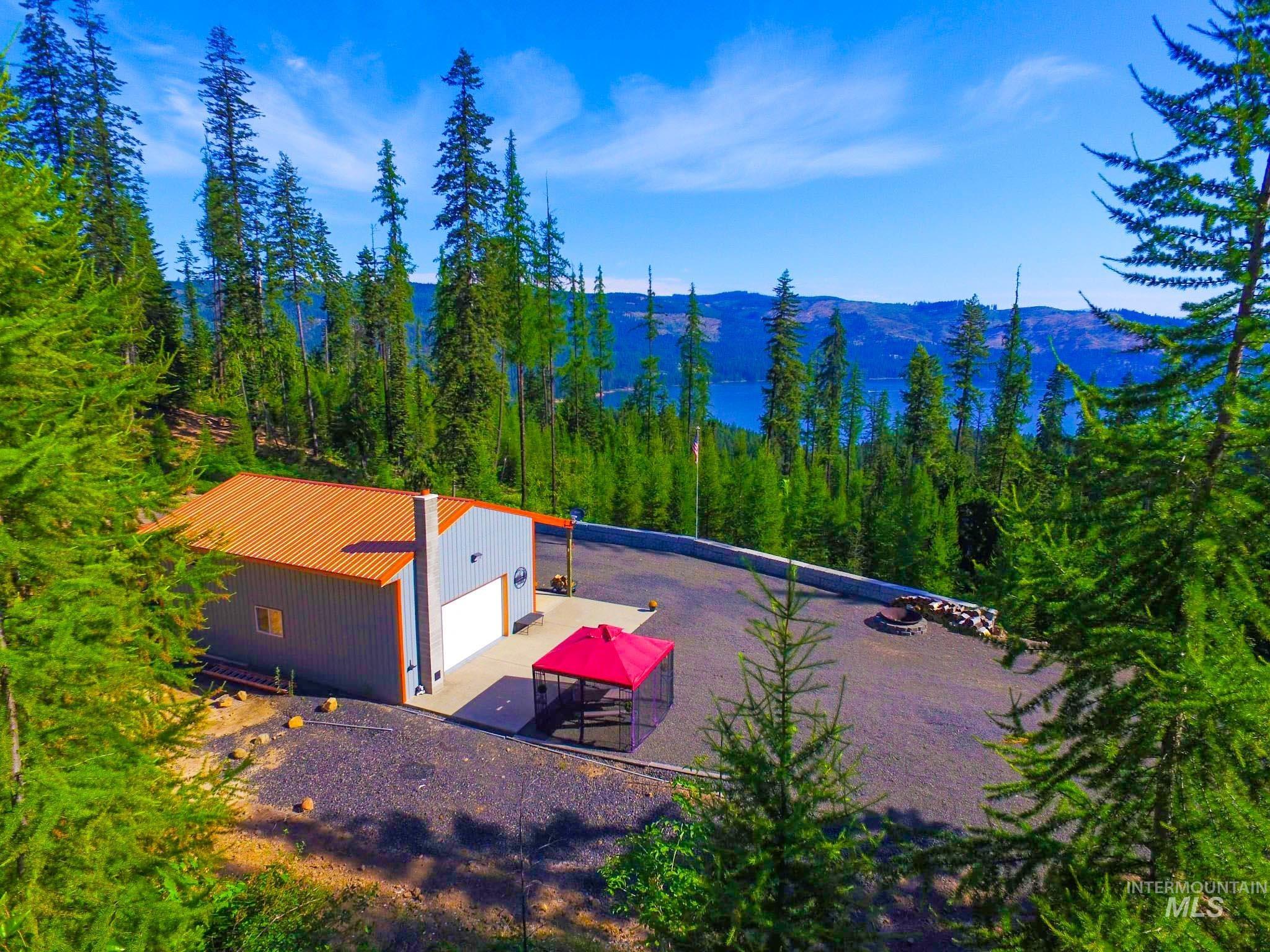 Aerial view of property and surrounding area featuring a mountain backdrop and a forest