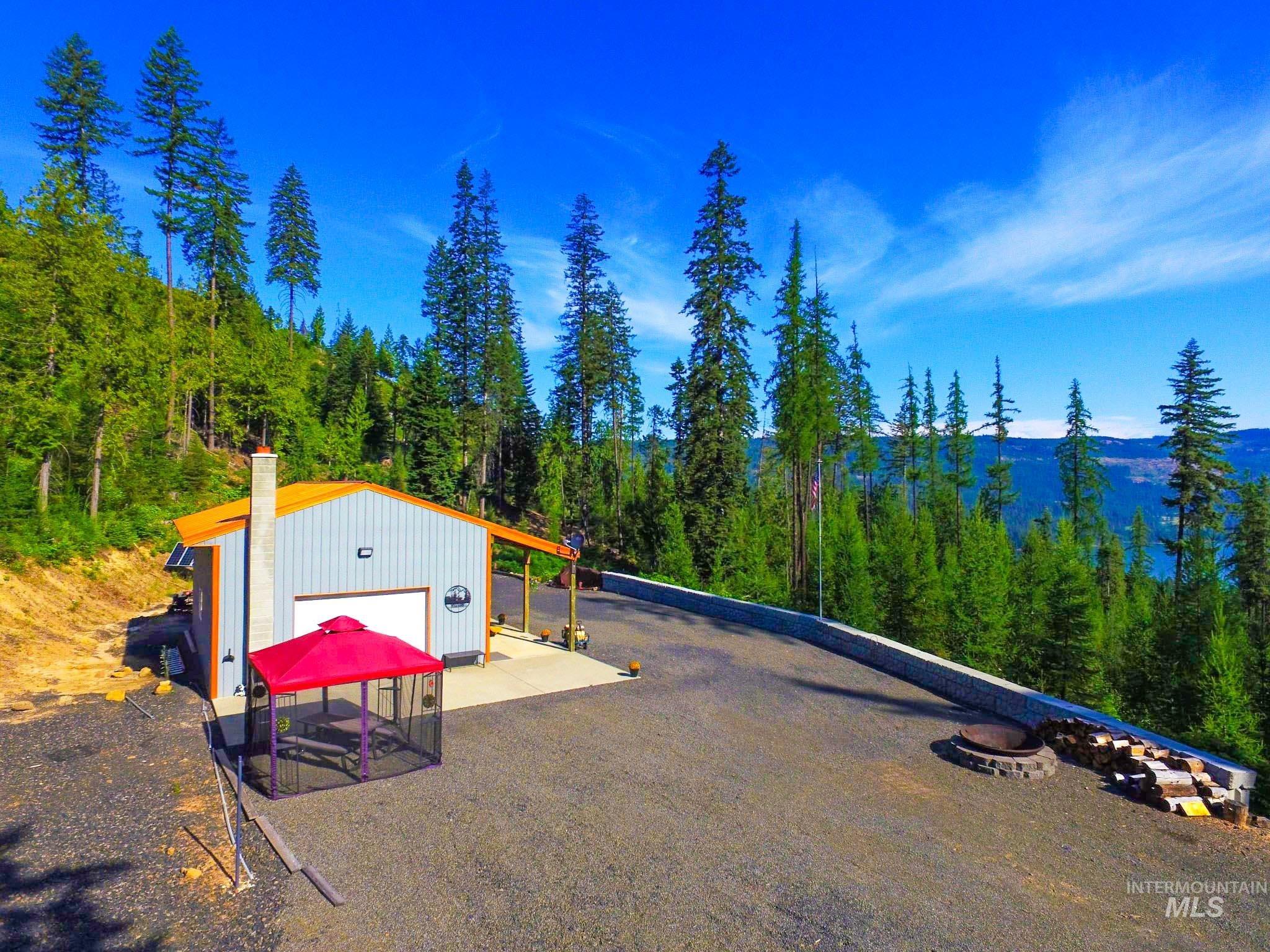 Exterior space with a garage, an outbuilding, a forest view, and driveway
