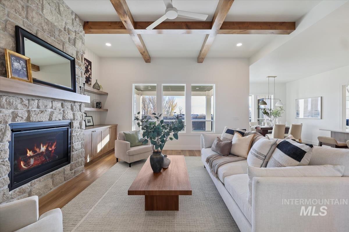 Living area with light wood-style floors, beamed ceiling, a fireplace, ceiling fan, and recessed lighting