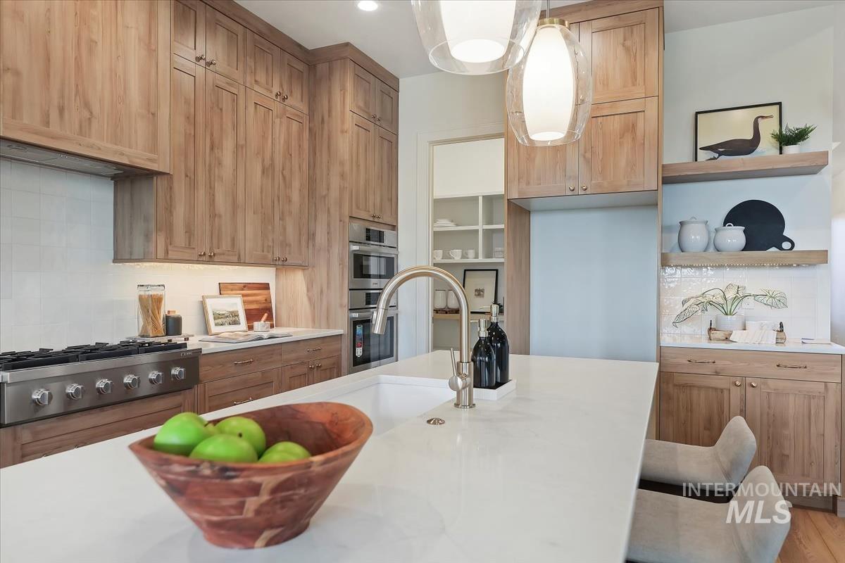 Kitchen featuring open shelves, backsplash, pendant lighting, and light stone countertops