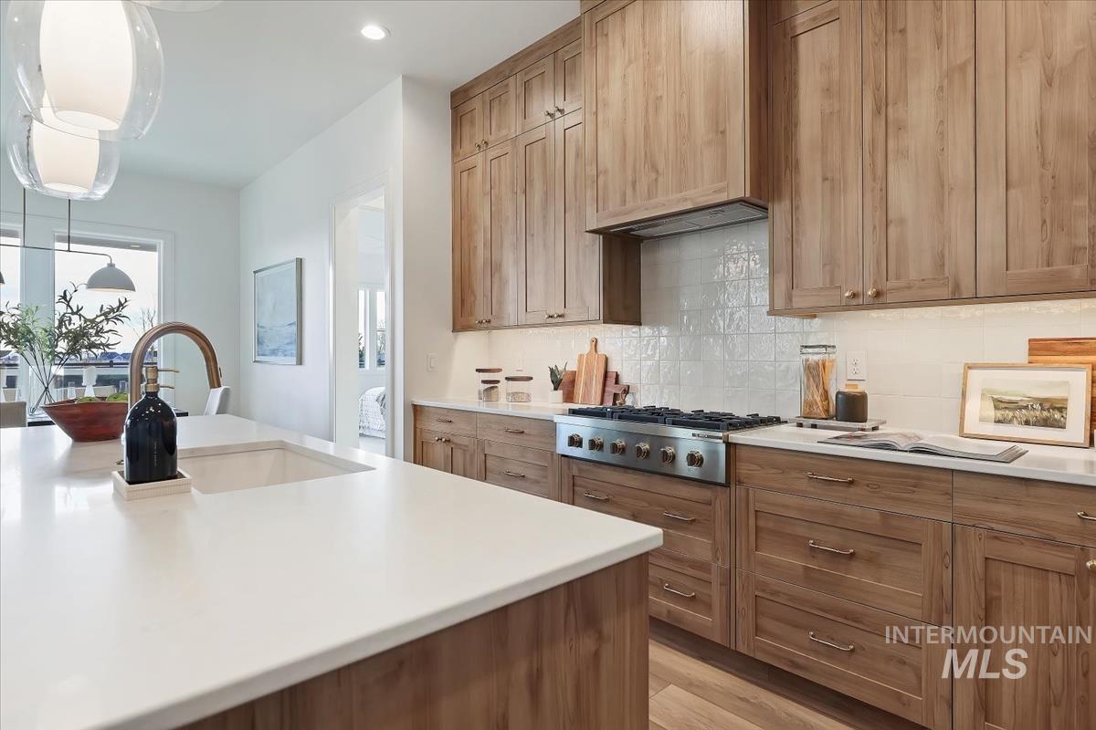Kitchen featuring tasteful backsplash, brown cabinetry, light wood finished floors, hanging light fixtures, and recessed lighting