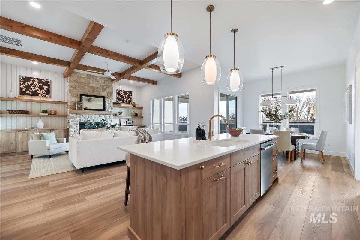 Kitchen with hanging light fixtures, light wood-style floors, coffered ceiling, beam ceiling, and open floor plan