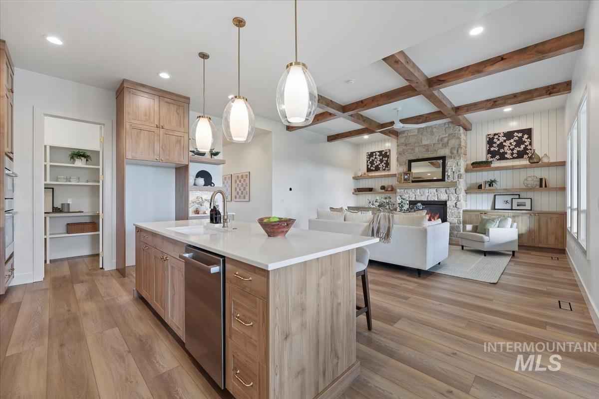 Kitchen featuring light wood-type flooring, open floor plan, decorative light fixtures, coffered ceiling, and beamed ceiling