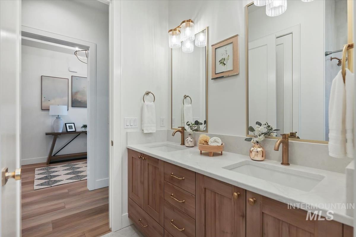 Full bath featuring double vanity and light wood-style flooring