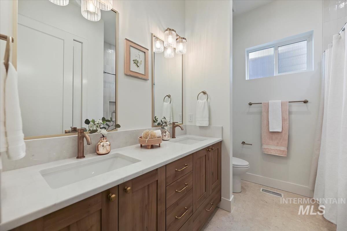 Full bath with double vanity, a shower with curtain, and light tile patterned floors