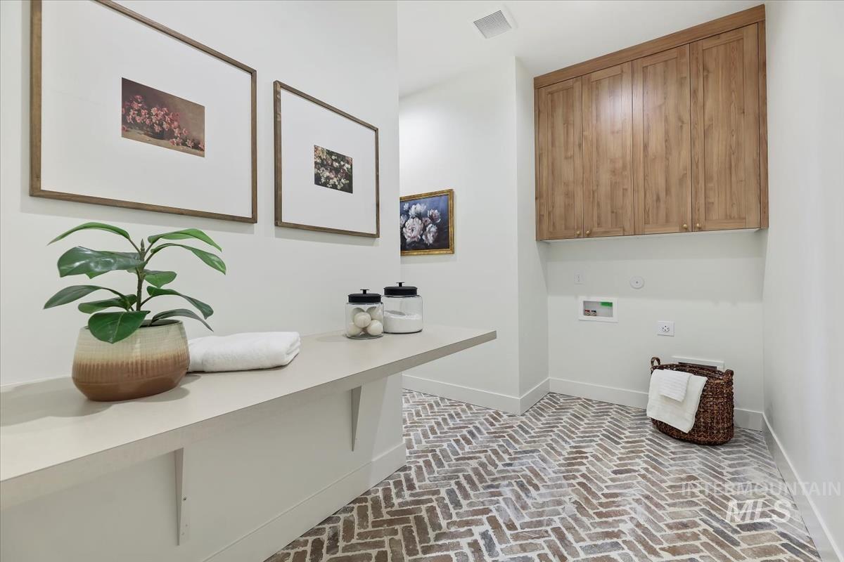 Washroom featuring brick floors, hookup for a washing machine, cabinet space, and hookup for a gas dryer