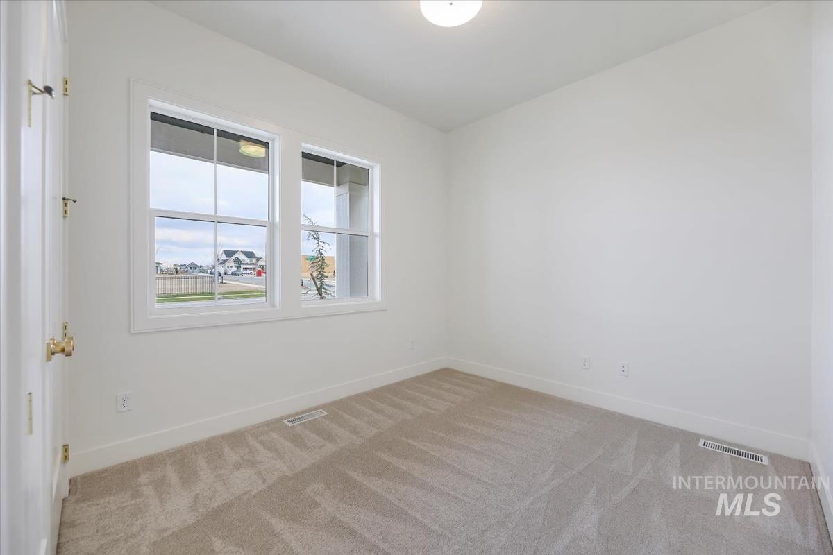 Spare room featuring light colored carpet and baseboards