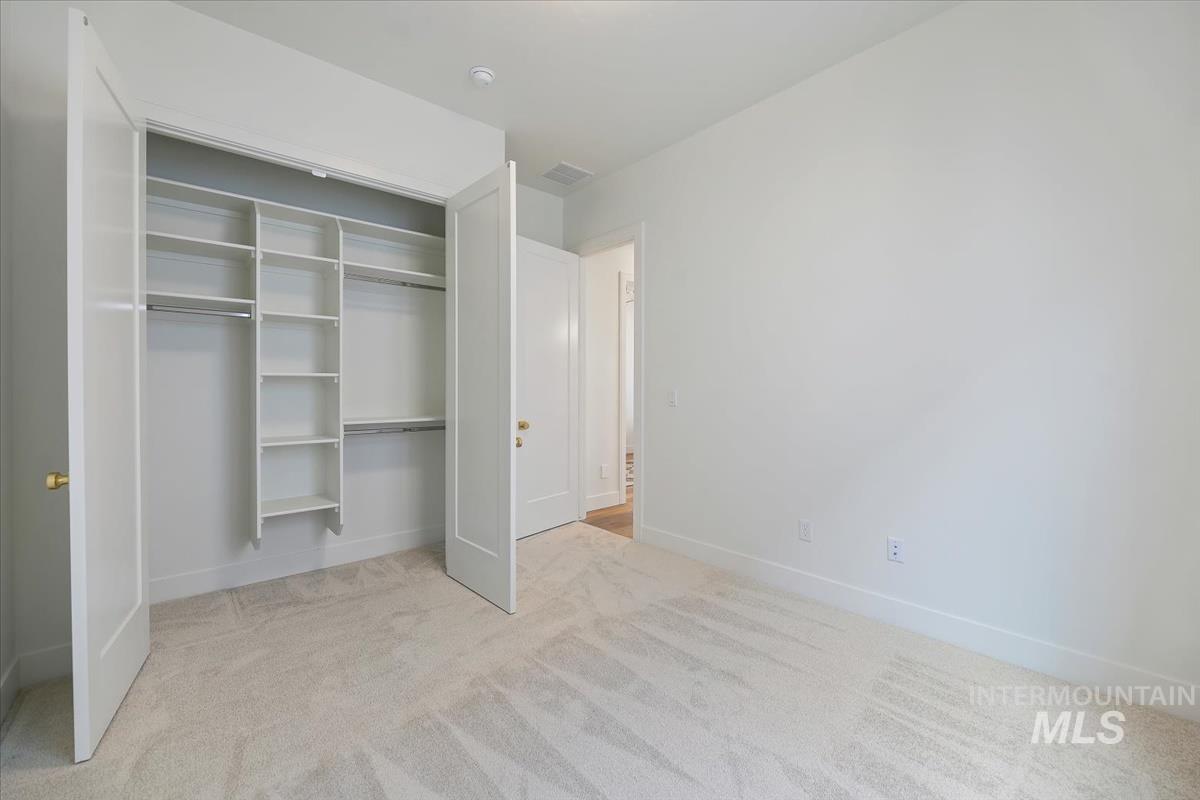 Unfurnished bedroom featuring light carpet and a closet