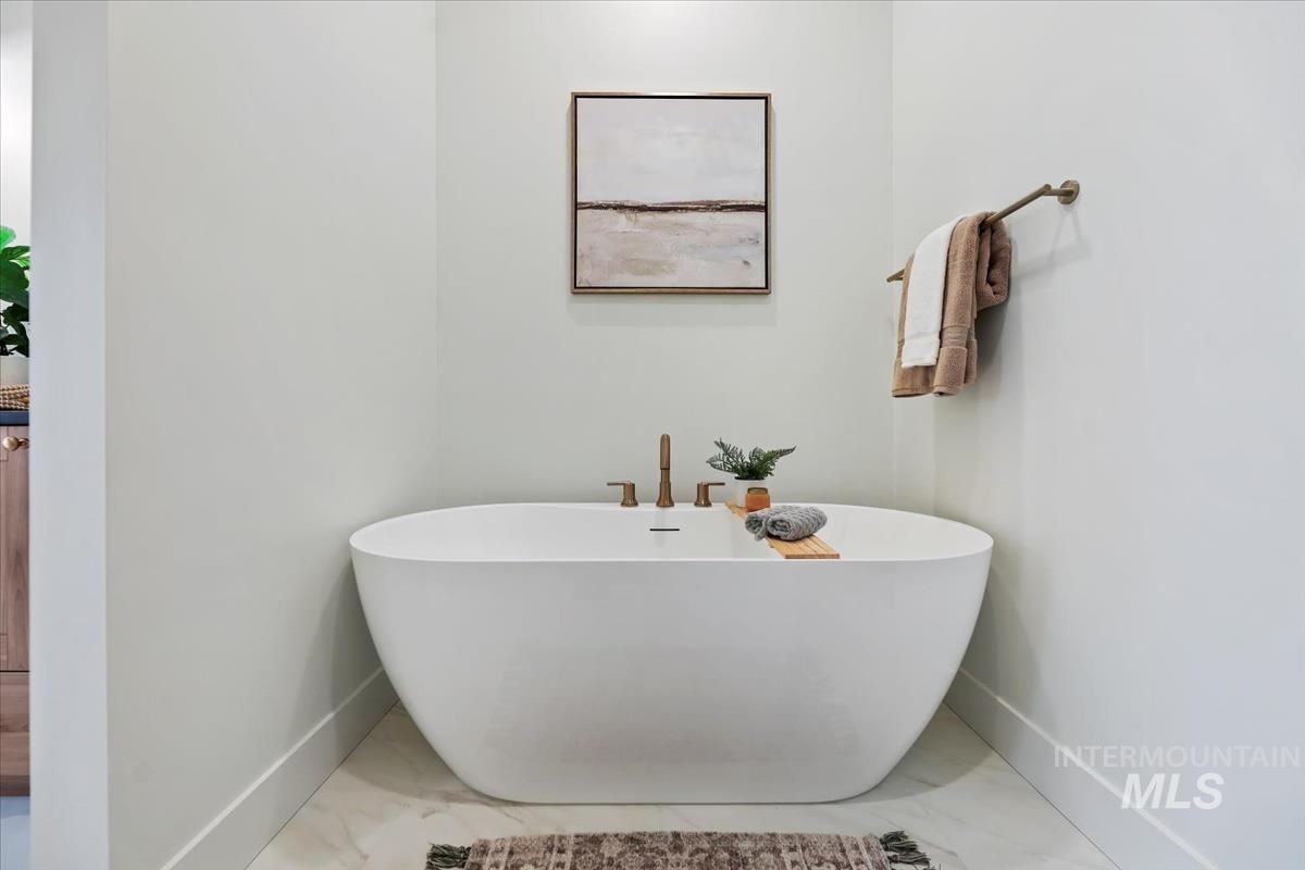 Full bath with a freestanding tub and baseboards
