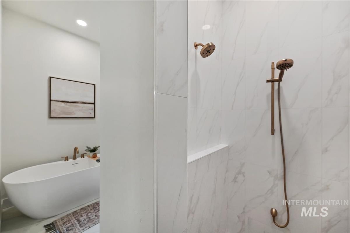 Bathroom featuring a marble finish shower and a freestanding tub