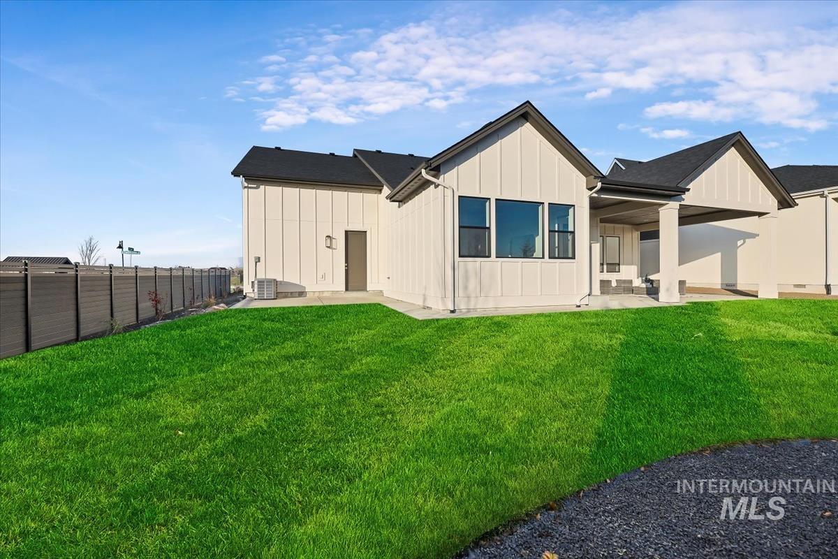 Rear view of house featuring board and batten siding, a fenced backyard, and a patio area