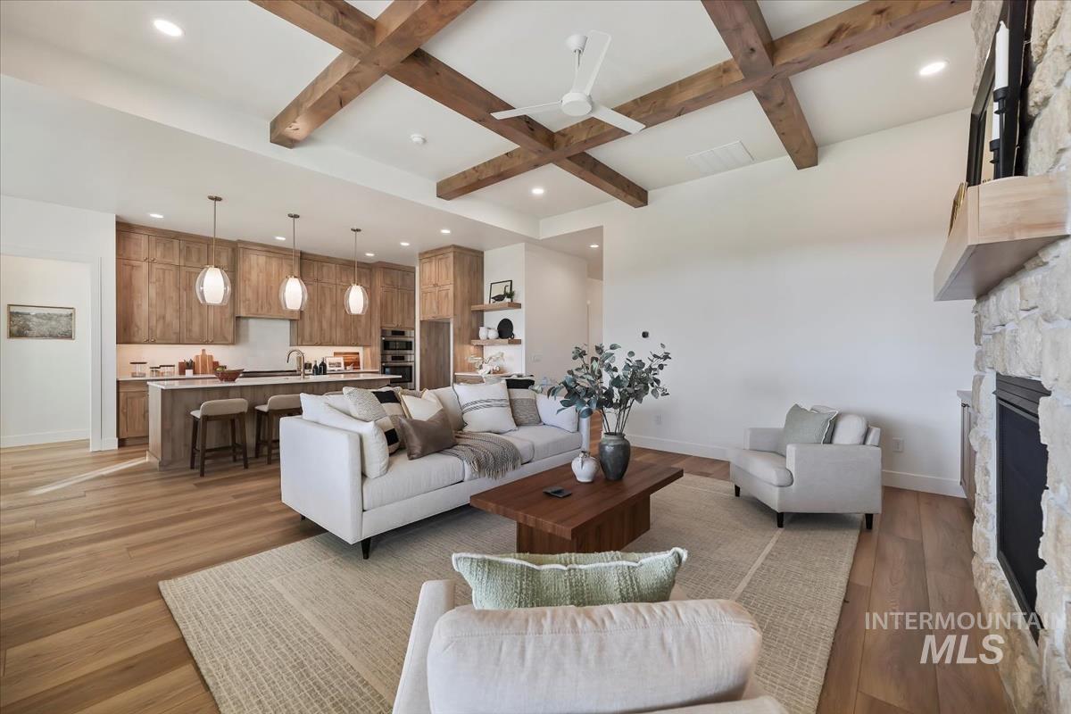 Living room with coffered ceiling, beam ceiling, light wood-style floors, ceiling fan, and recessed lighting
