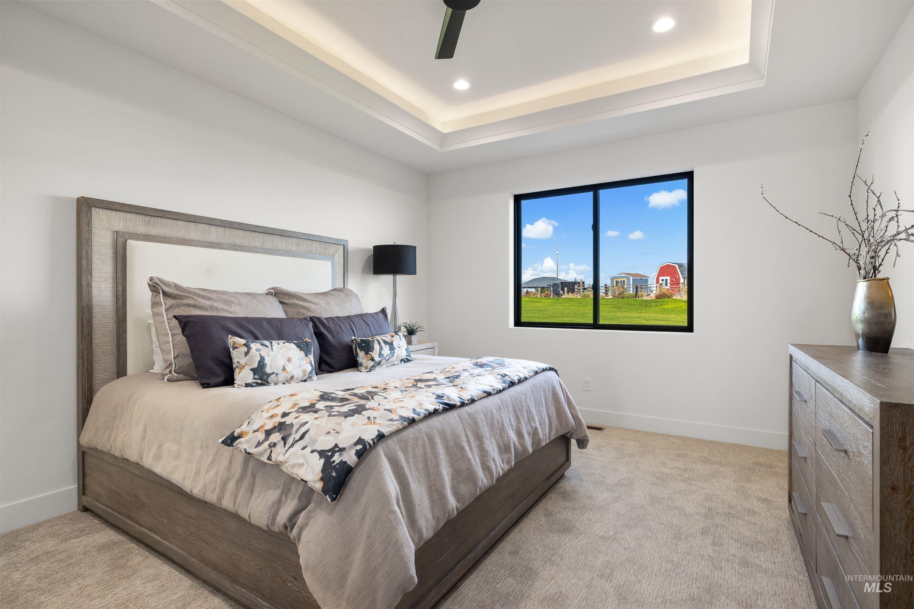 Bedroom featuring light carpet, ceiling fan, a tray ceiling, and recessed lighting