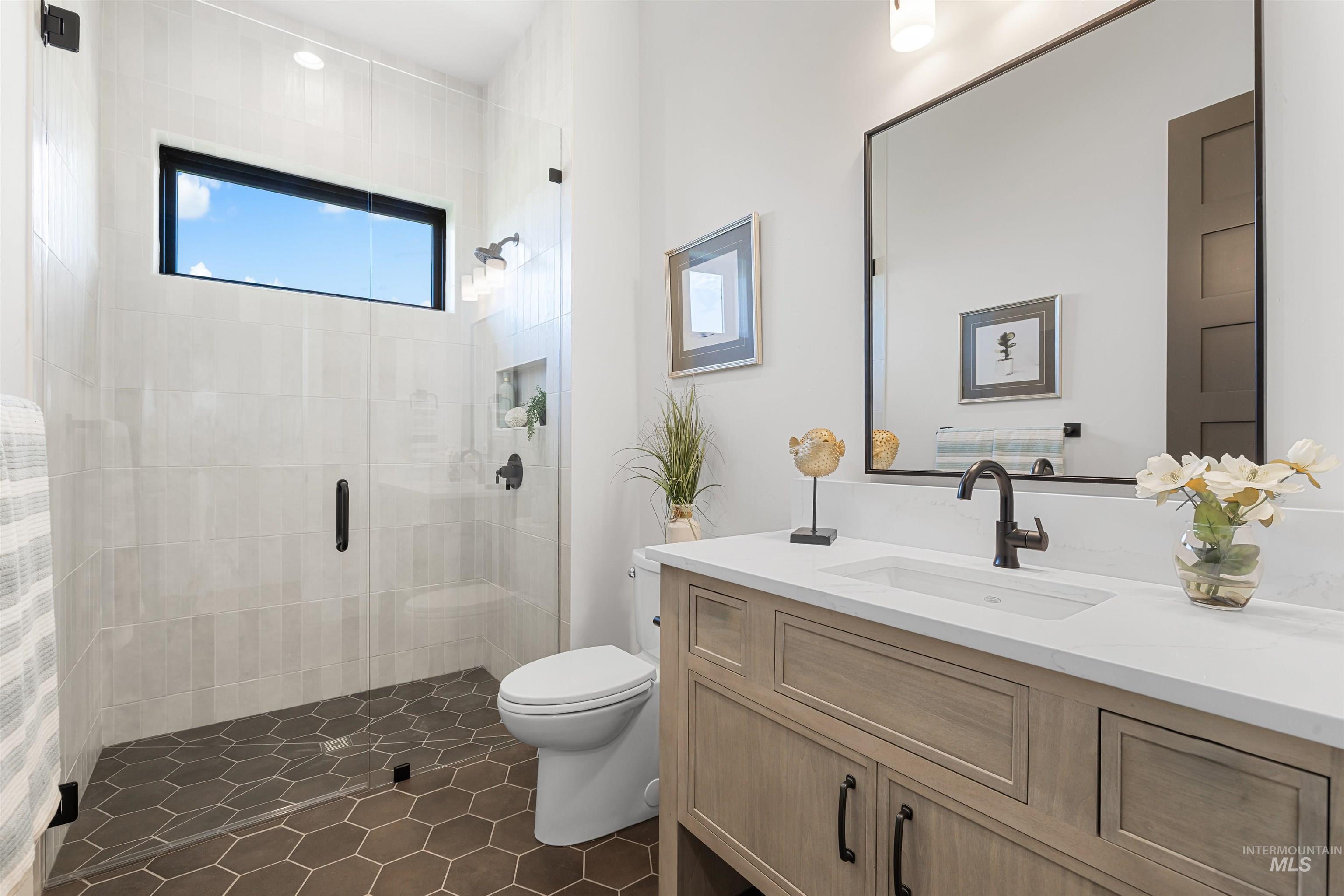 Bathroom with a stall shower, vanity, and dark tile patterned floors