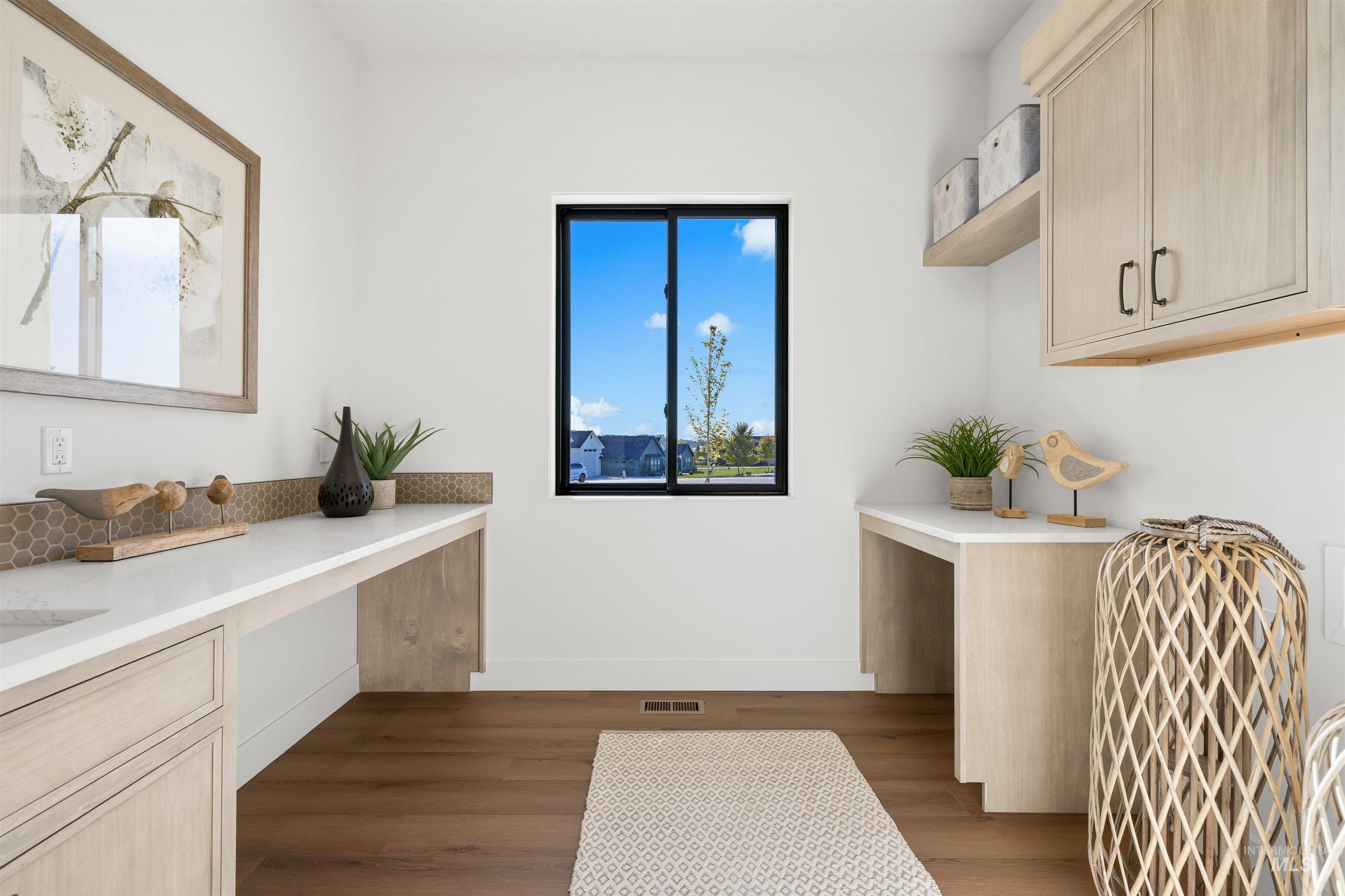 Laundry area featuring dark wood finished floors, cabinet space, and a desk