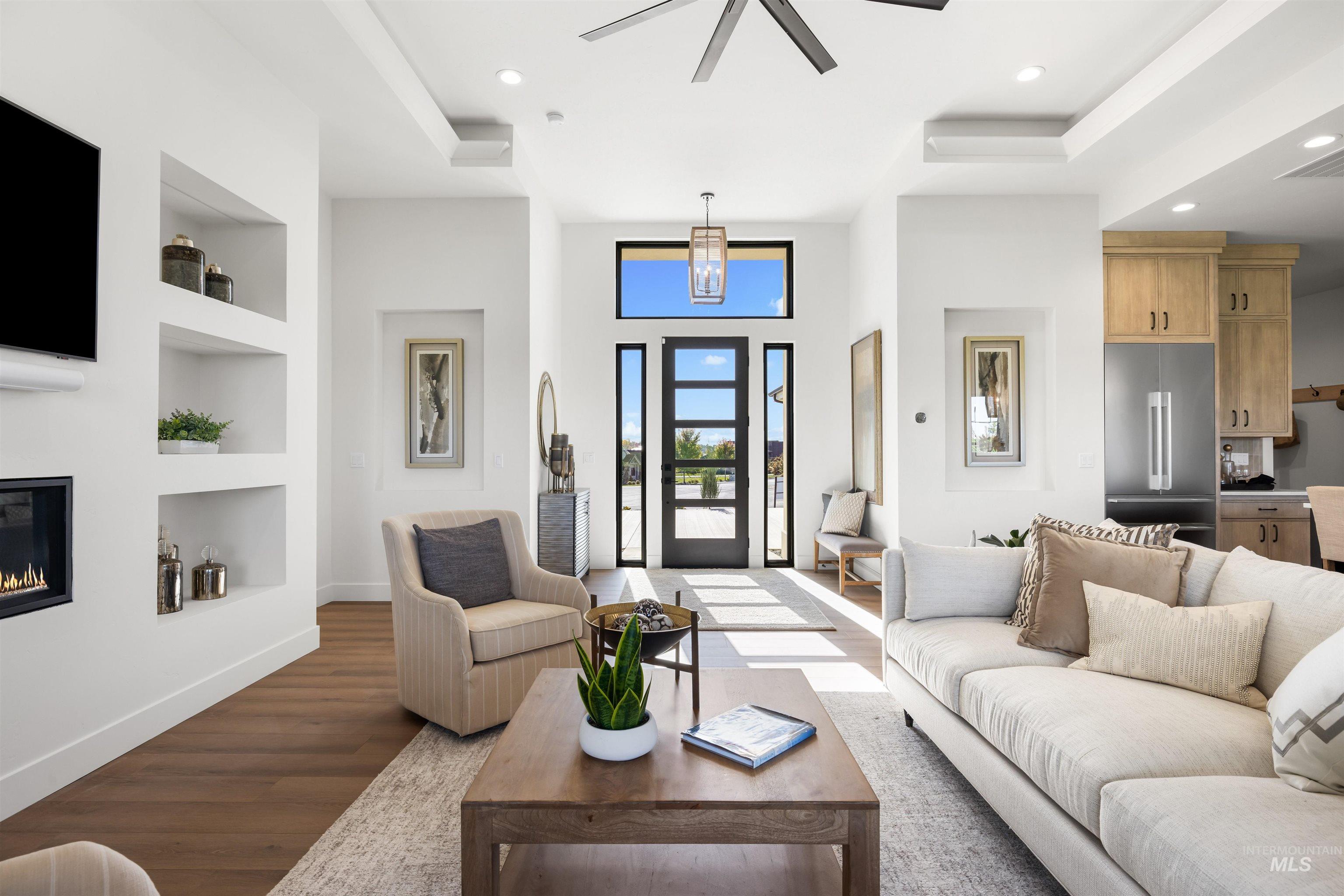 Living area with recessed lighting, built in features, wood finished floors, a glass covered fireplace, and a ceiling fan