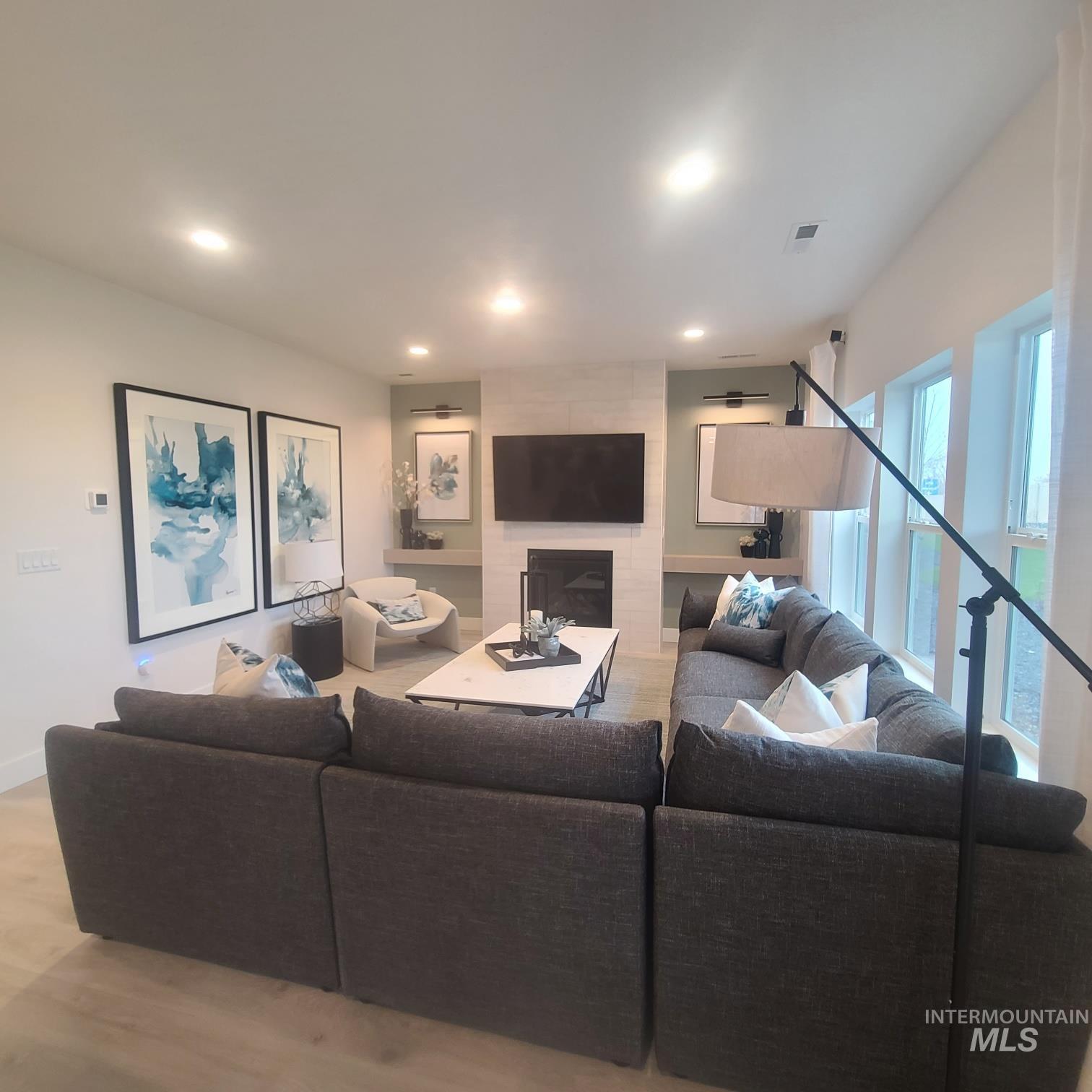Living room featuring light wood-style flooring, recessed lighting, and a fireplace