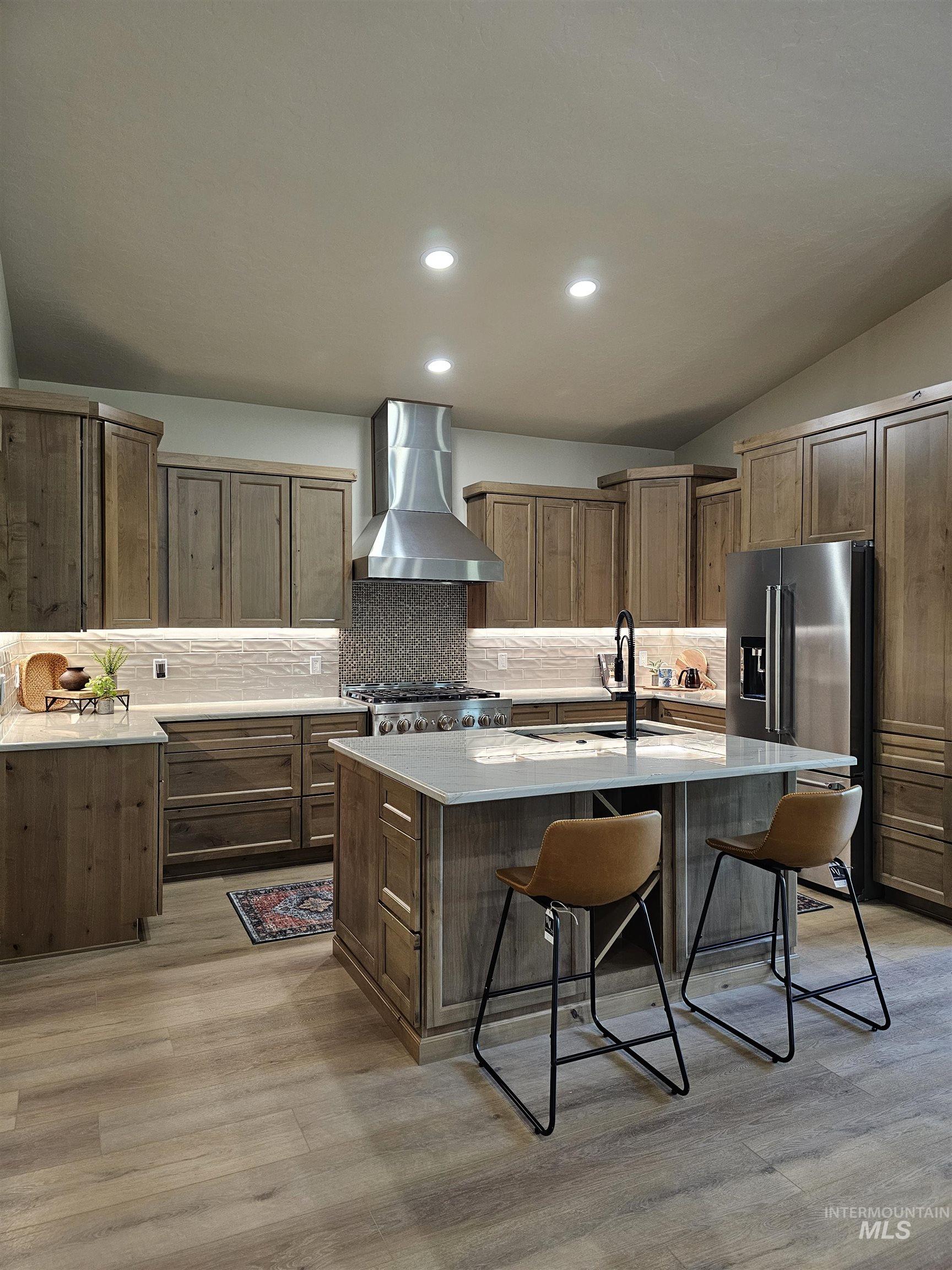 Kitchen island with sink, dishwasher, a kitchen breakfast bar, wine bottle storage area.