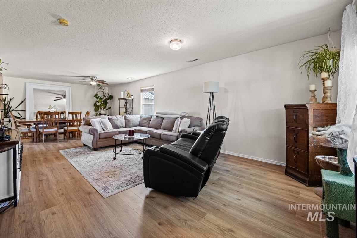 Living area featuring light wood-style flooring, ceiling fan, and a textured ceiling