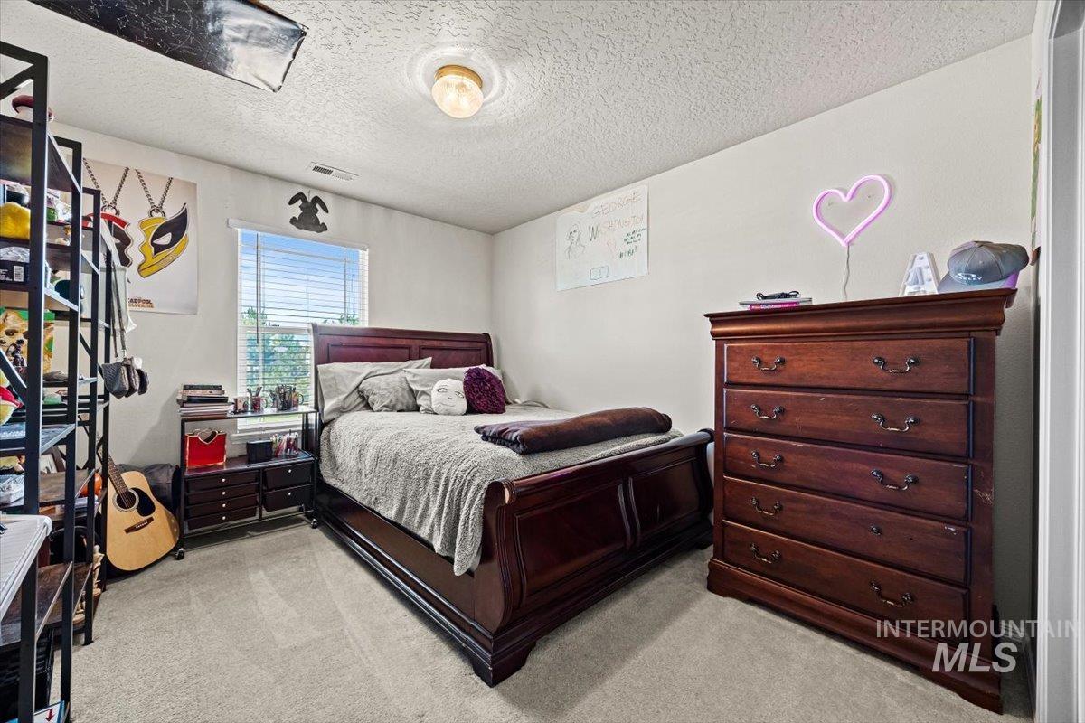 Bedroom with light colored carpet and a textured ceiling