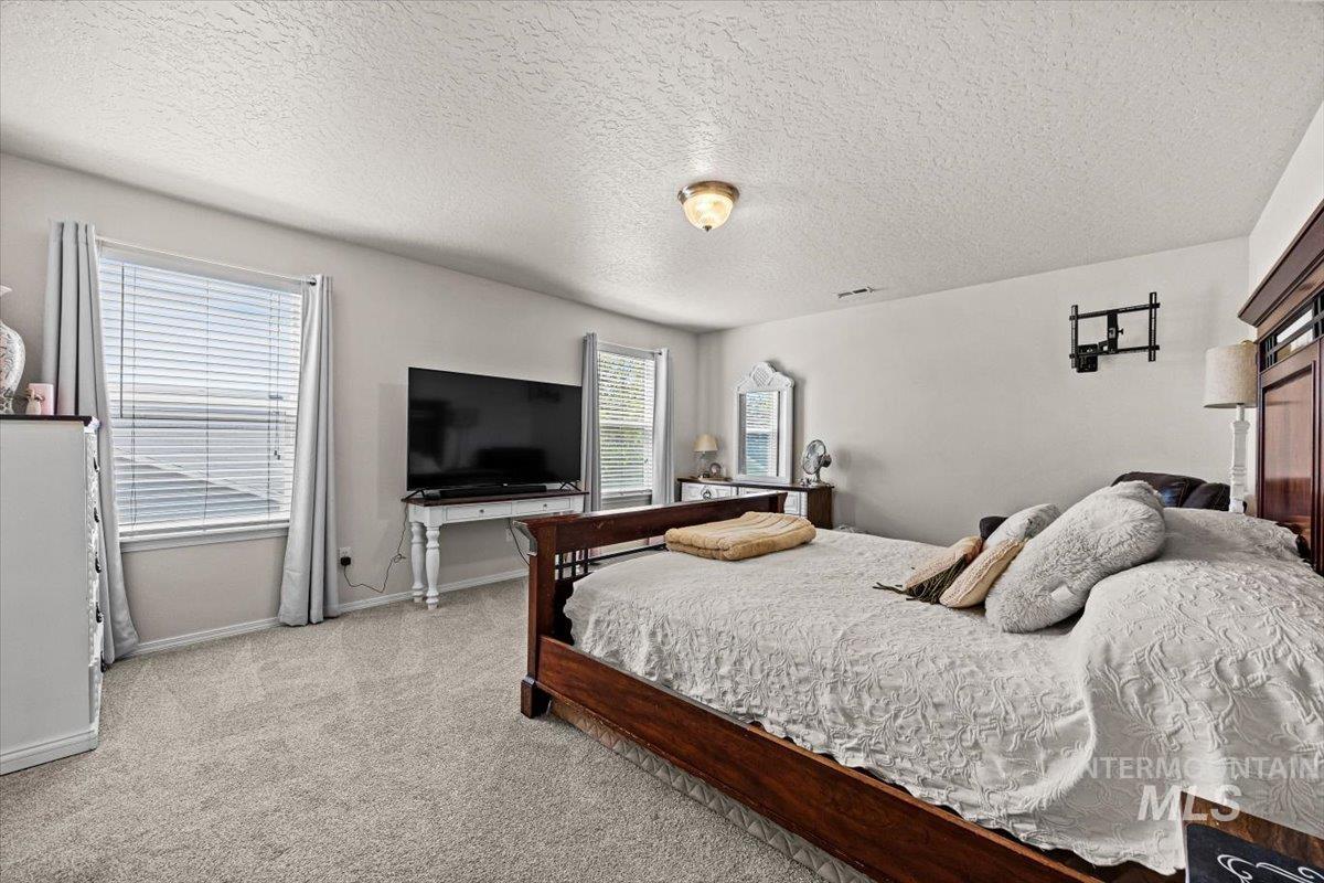 Bedroom featuring light colored carpet and a textured ceiling