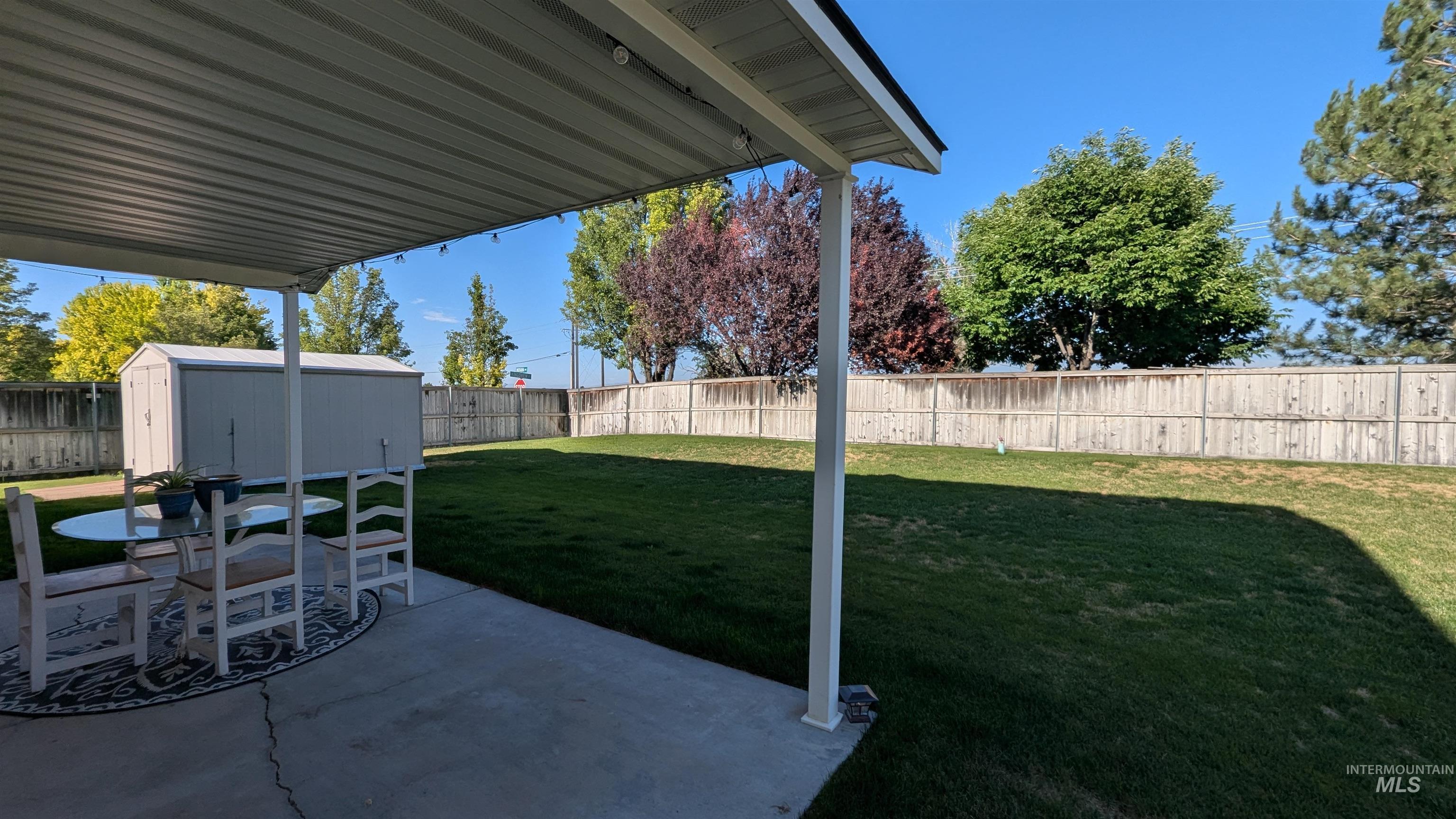 Fenced backyard featuring a shed and a patio