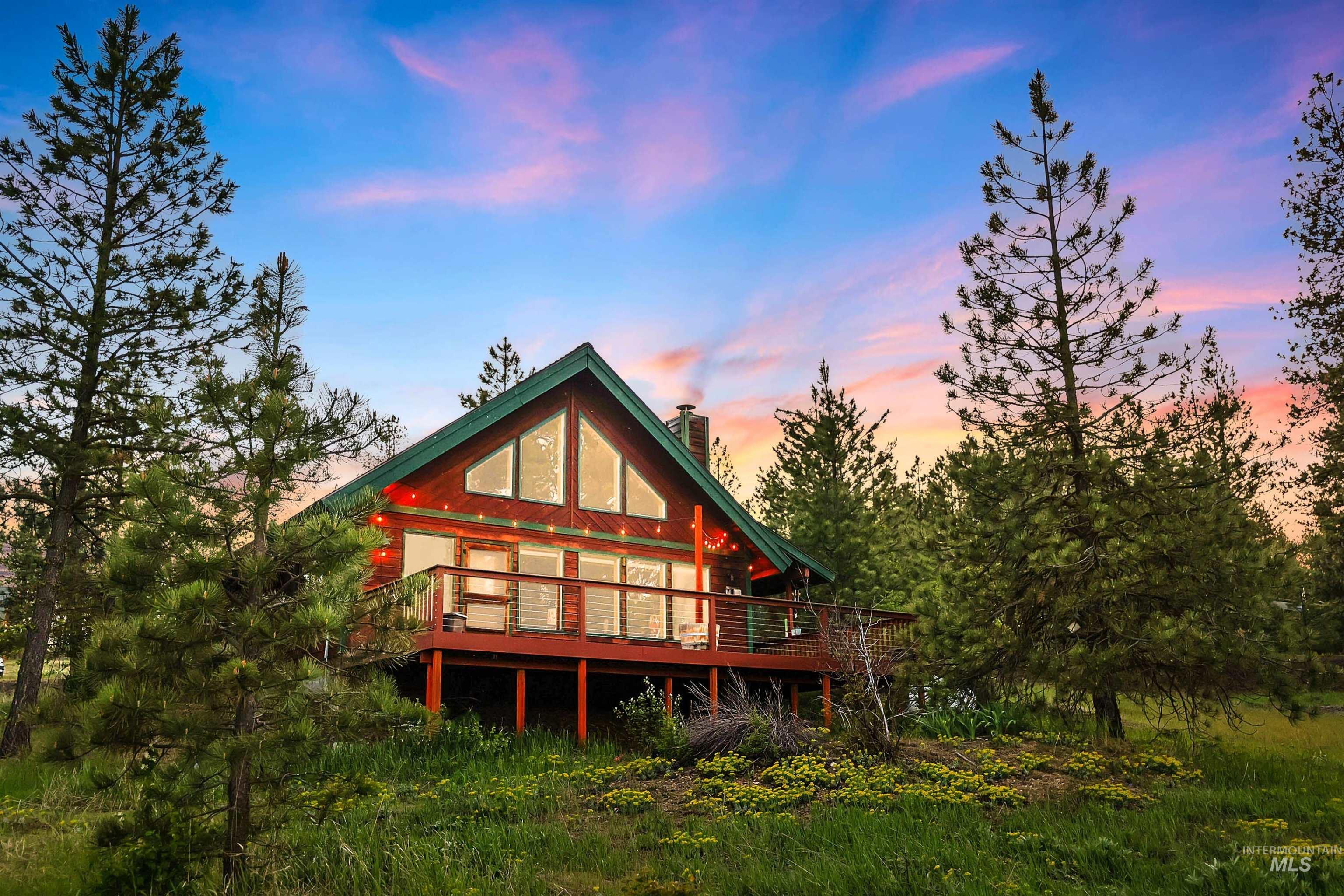 A frame cabin and newer deck looking out onto meadow views.