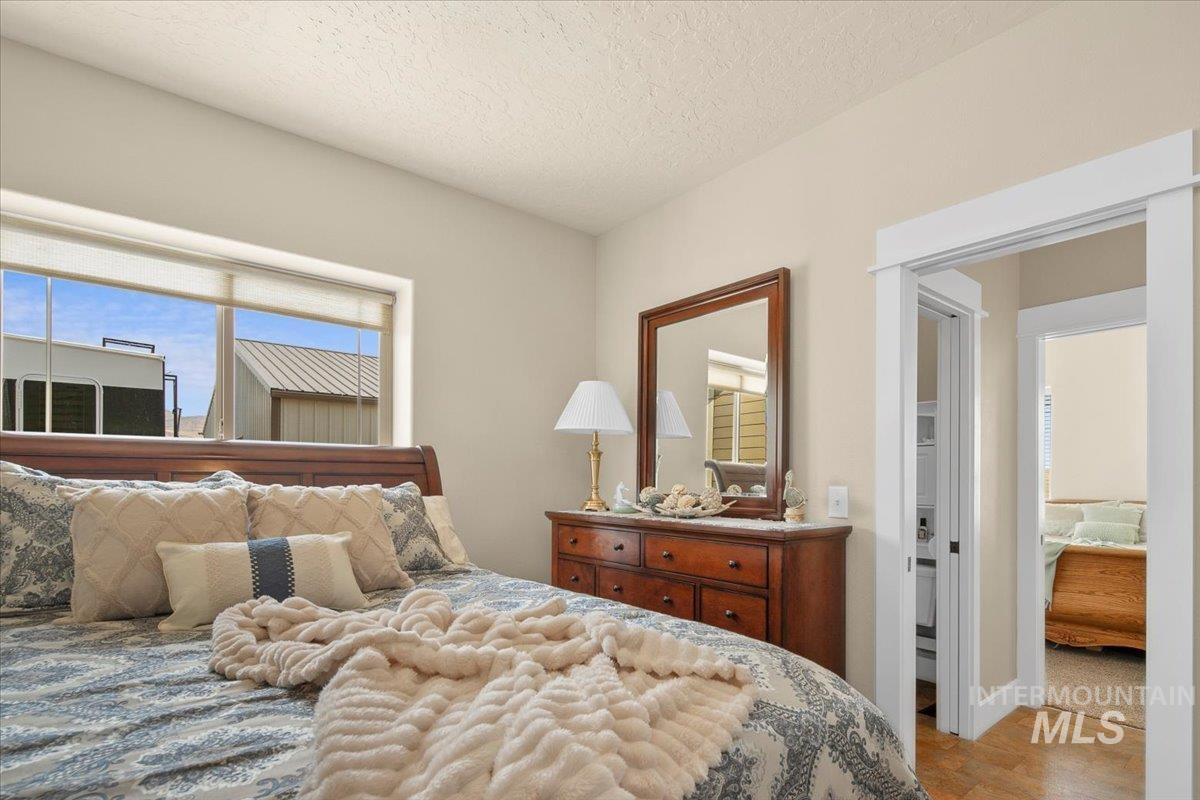 Bedroom with multiple windows, a textured ceiling, and wood finished floors