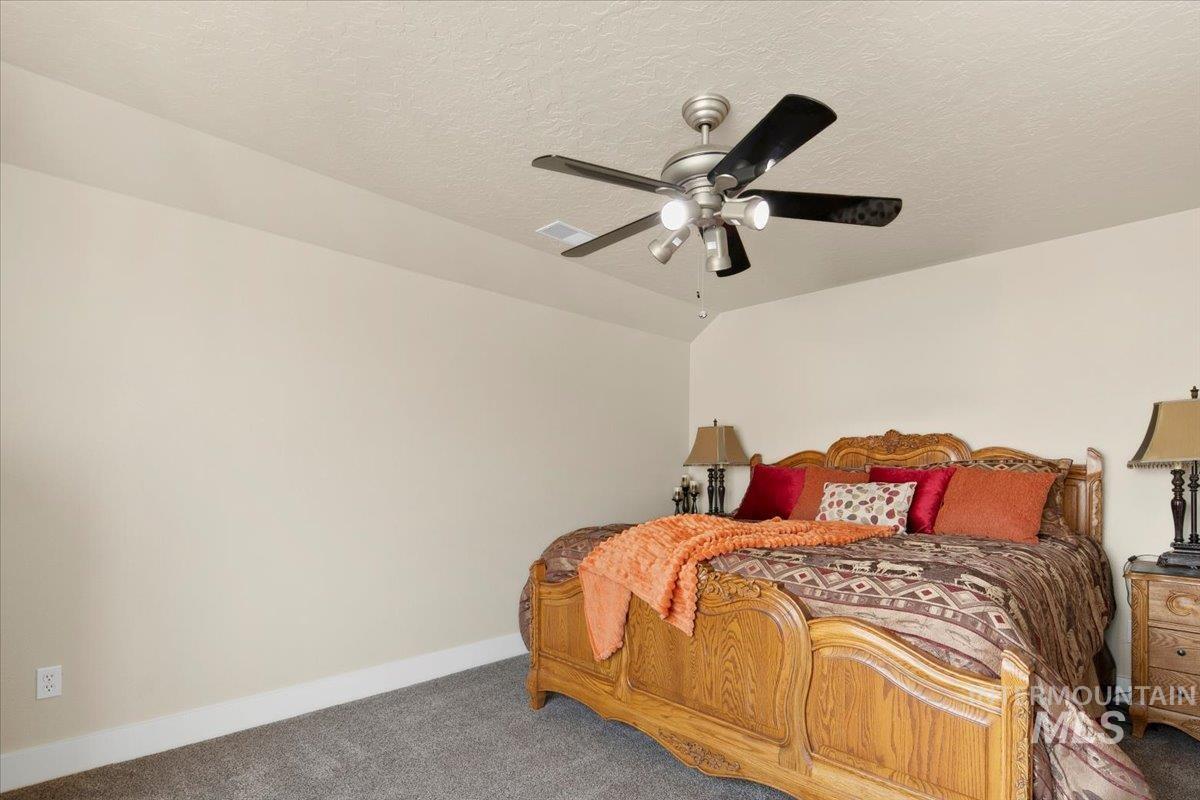 Bedroom featuring carpet, a textured ceiling, and ceiling fan
